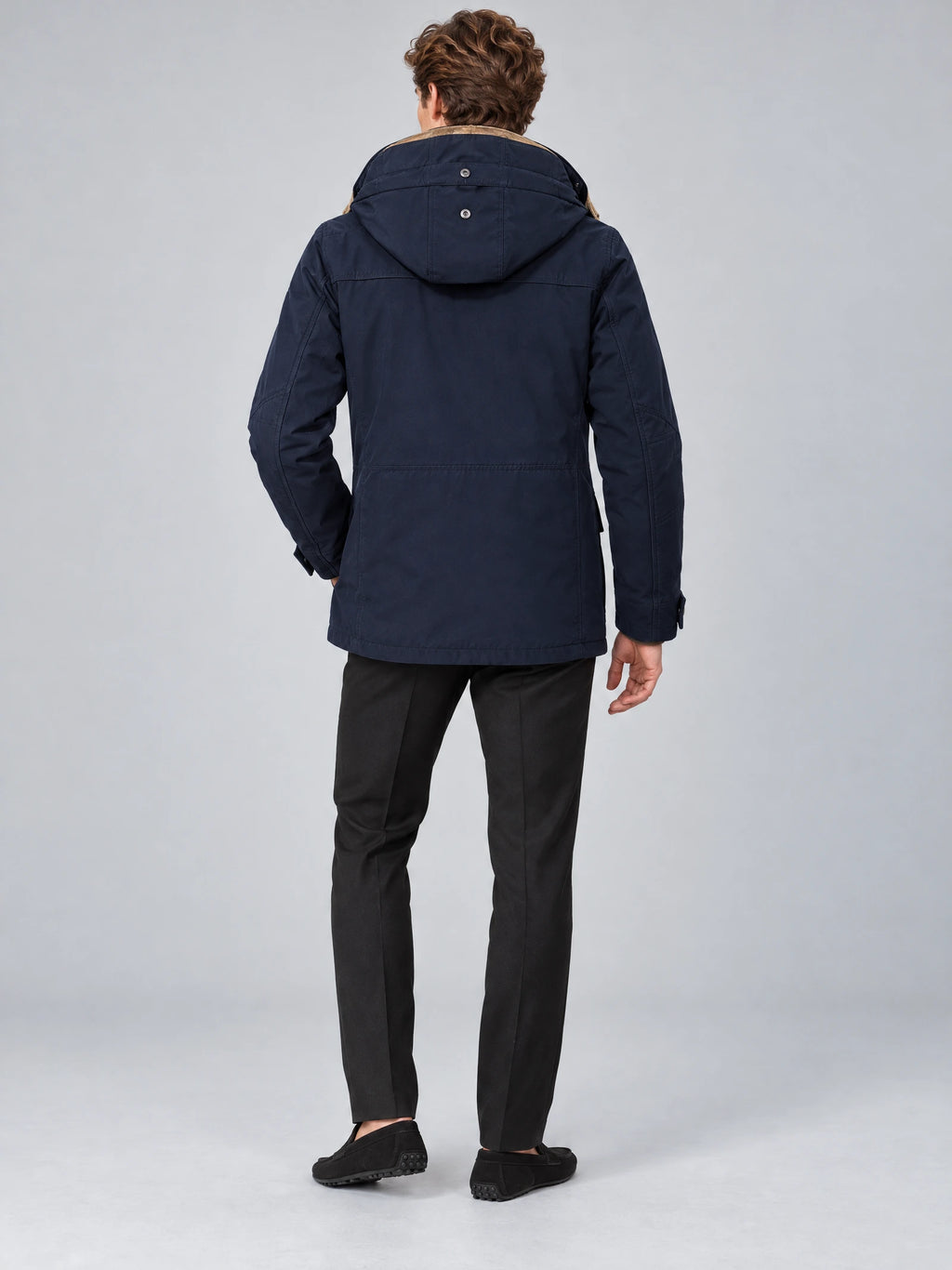 Rear studio view of a model wearing a Navy heavy winter jacket with a buttoned hood and stitched back panel.