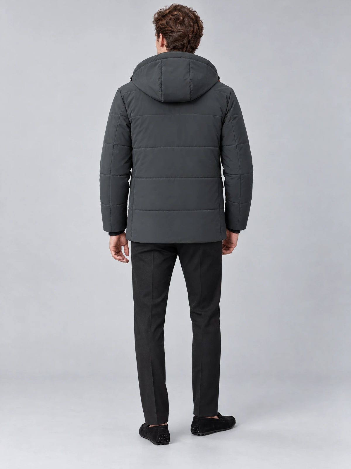 Rear view of a model wearing a Gray Heavy Winter Jacket with a quilted hood and hip-length padded design.