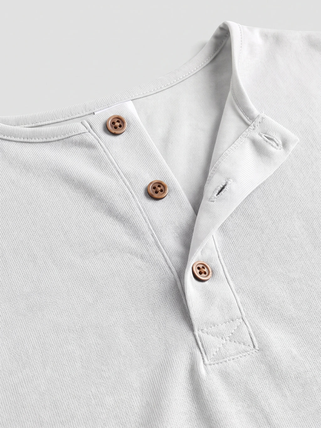 Close-up of the White men's Henley T-shirt showing the ribbed neckline, button placket, and stitched reinforcement.