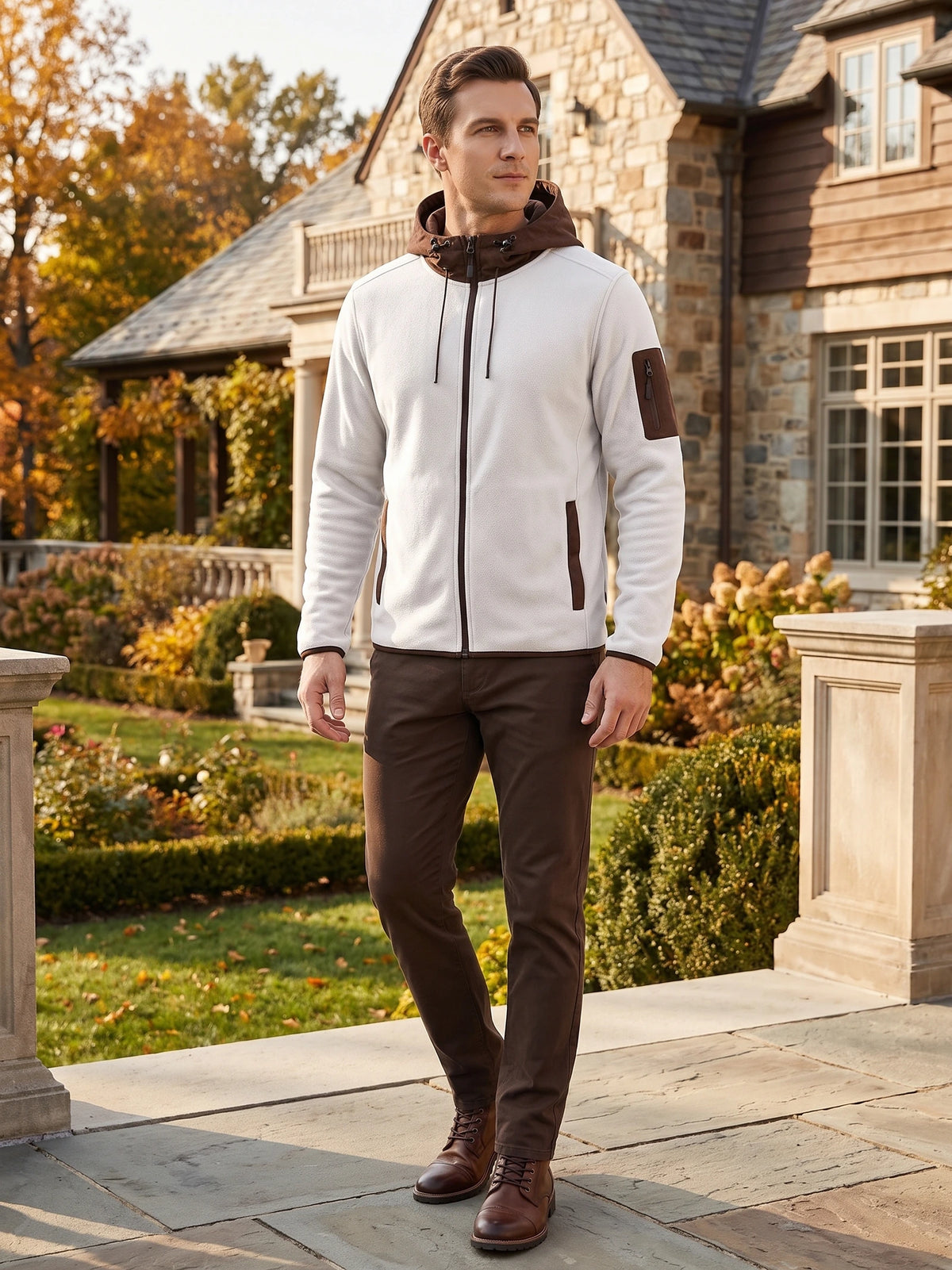 Model wearing a White full-zip hooded Fleece Jacket with zip pockets while walking outside a stone house.
