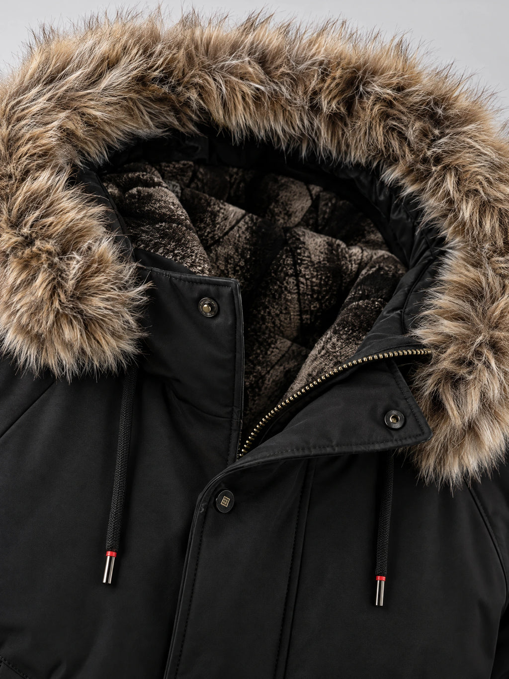 Close-up of the Black Hooded Fur Collar Jacket showing the fur-trimmed hood, fleece lining, zipper, and snap-button storm flap.