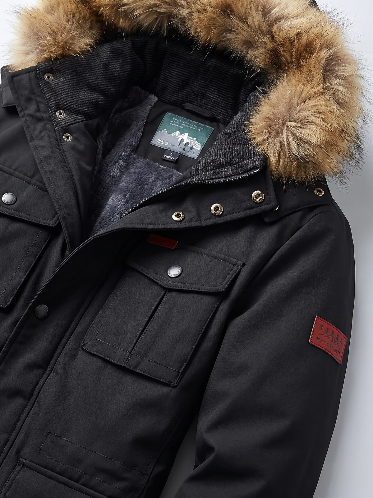 Black men’s parka detail showing a fur-trimmed hood, plush lining, snap-button storm flap, and flap pockets.