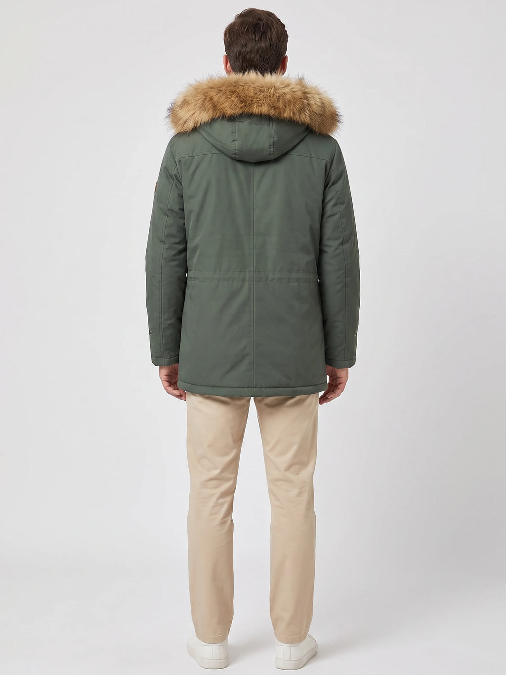 Rear studio view of a model wearing a Green men's parka with a fur-trimmed hood and back seam detailing.