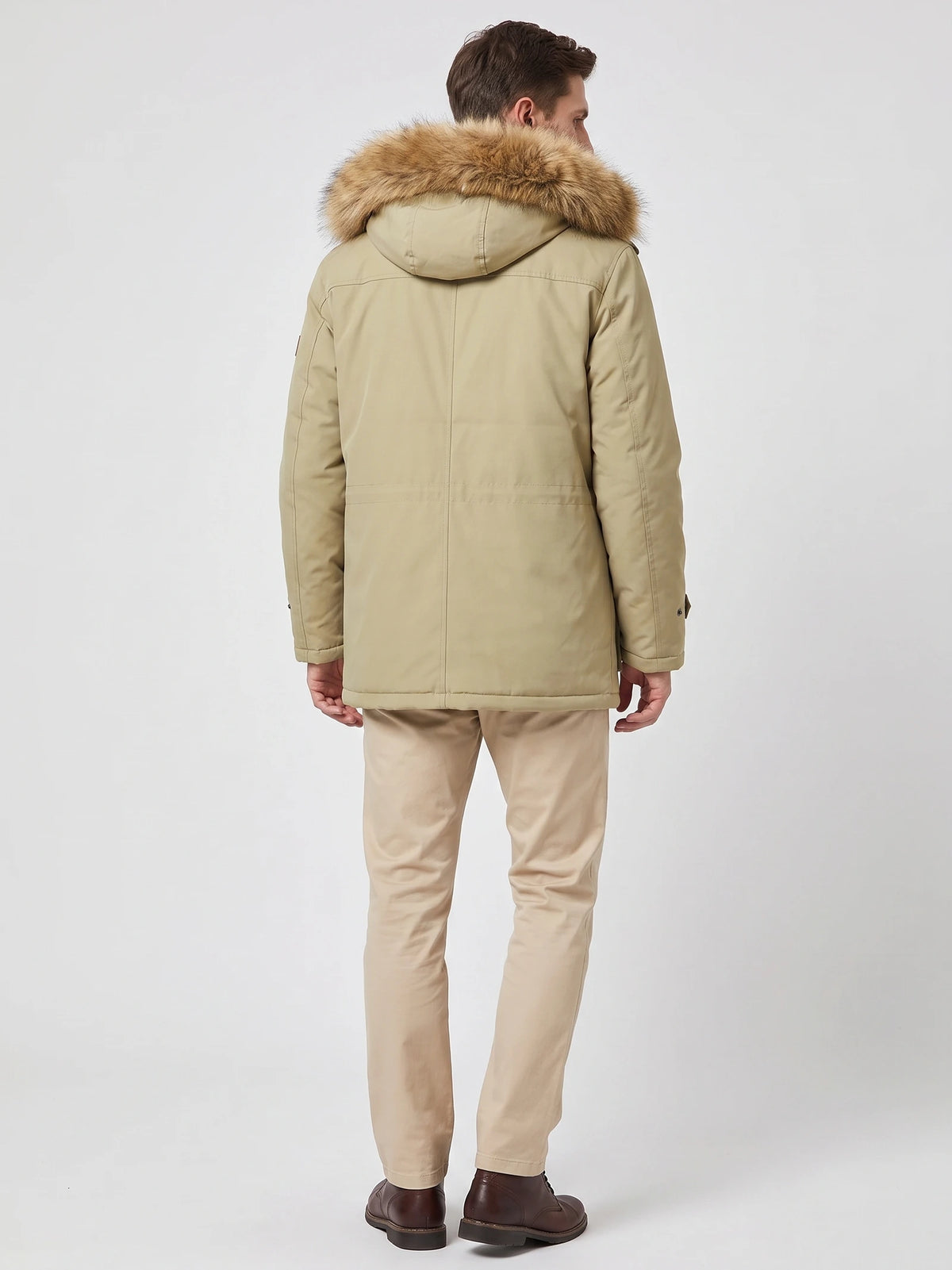 Back view of a model wearing a Khaki men's parka with a fur-trimmed hood and stitched rear paneling.