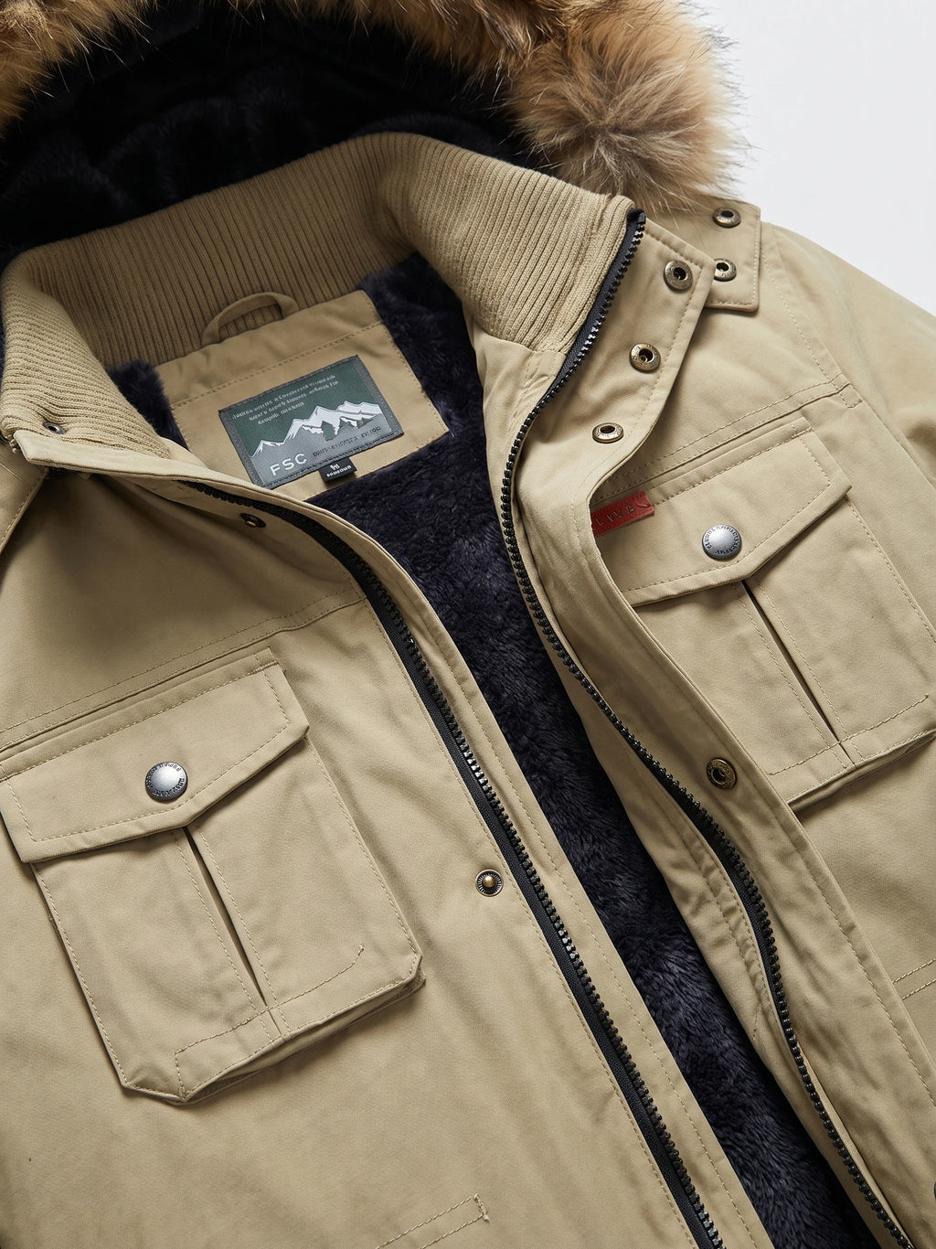 Khaki men's parka close-up showing the faux-fur-trimmed hood, ribbed collar, dark plush lining, zip front, and flap chest pockets.