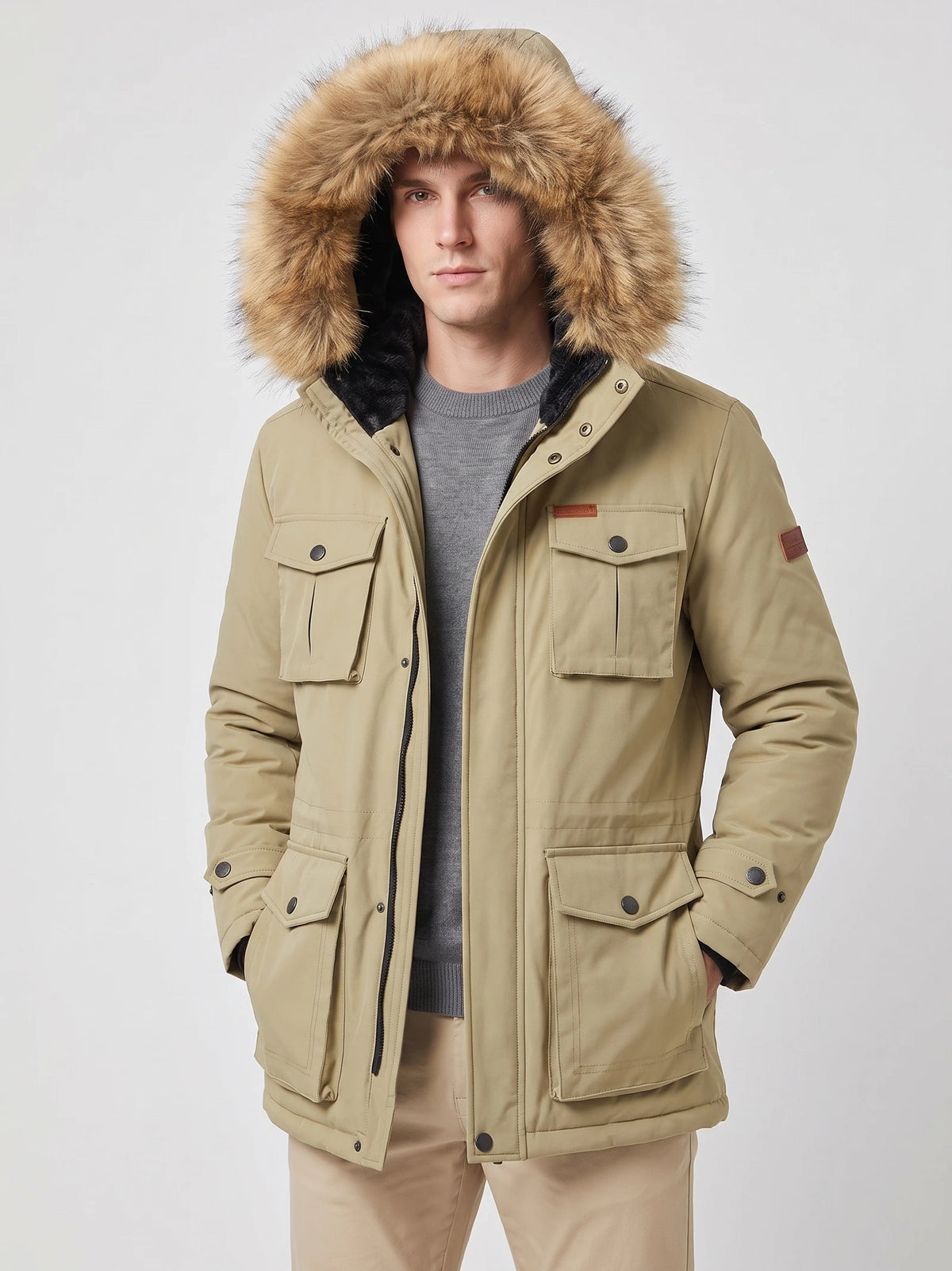 Front studio view of a model wearing a Khaki men's parka with a fur-trimmed hood and flap pockets.