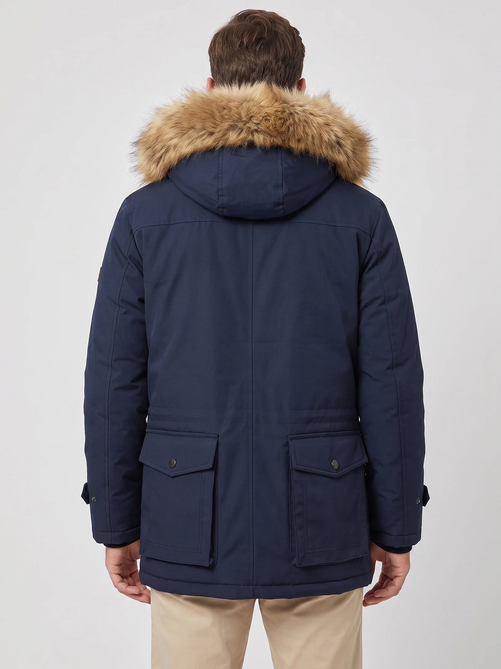 Rear view of a model wearing a Navy men's parka with a fur-trimmed hood and two flap back pockets.