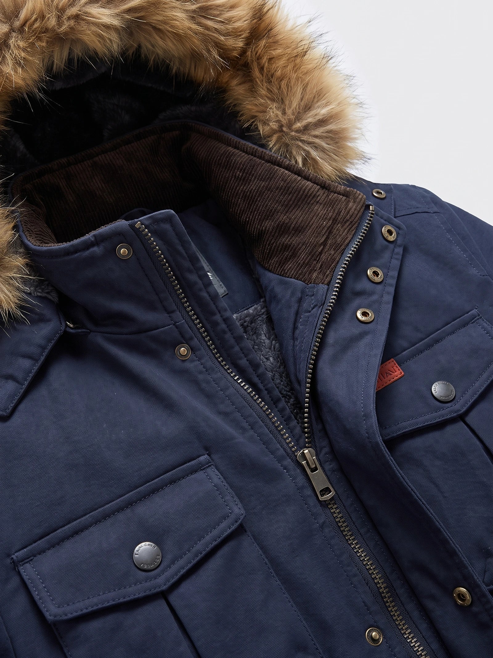 Close-up of a Navy men’s parka showing the fur-trimmed hood, ribbed inner collar, zipper, snap placket, and flap pockets.