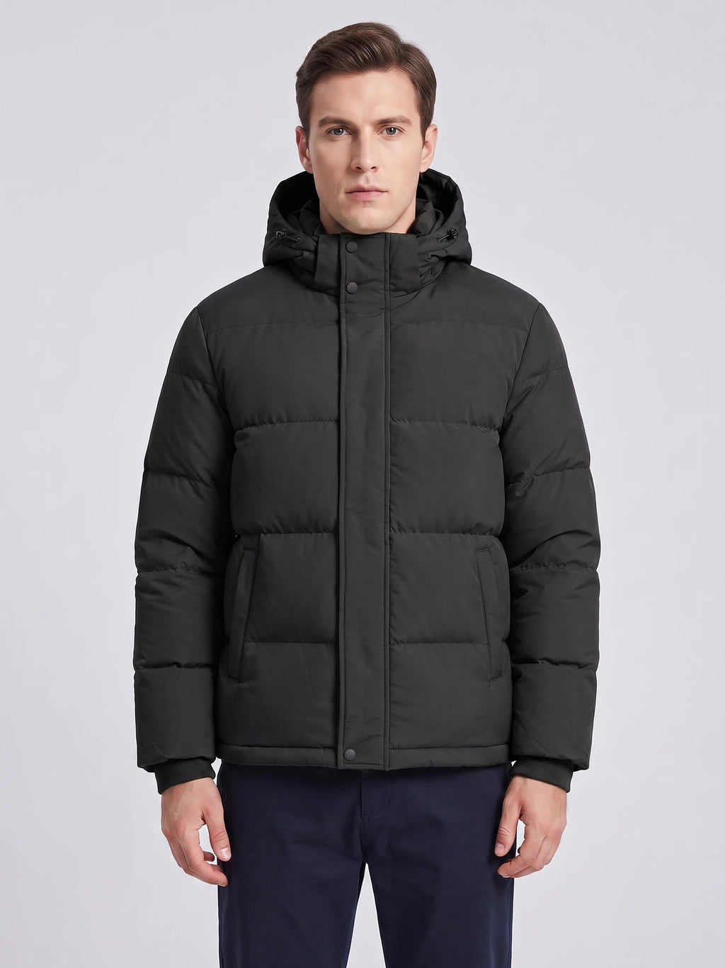 Front studio view of a model wearing a Black hooded puffer jacket with a snap-front placket and zippered pockets.