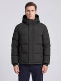 Front studio view of a model wearing a Black hooded puffer jacket with a snap-front placket and zippered pockets.