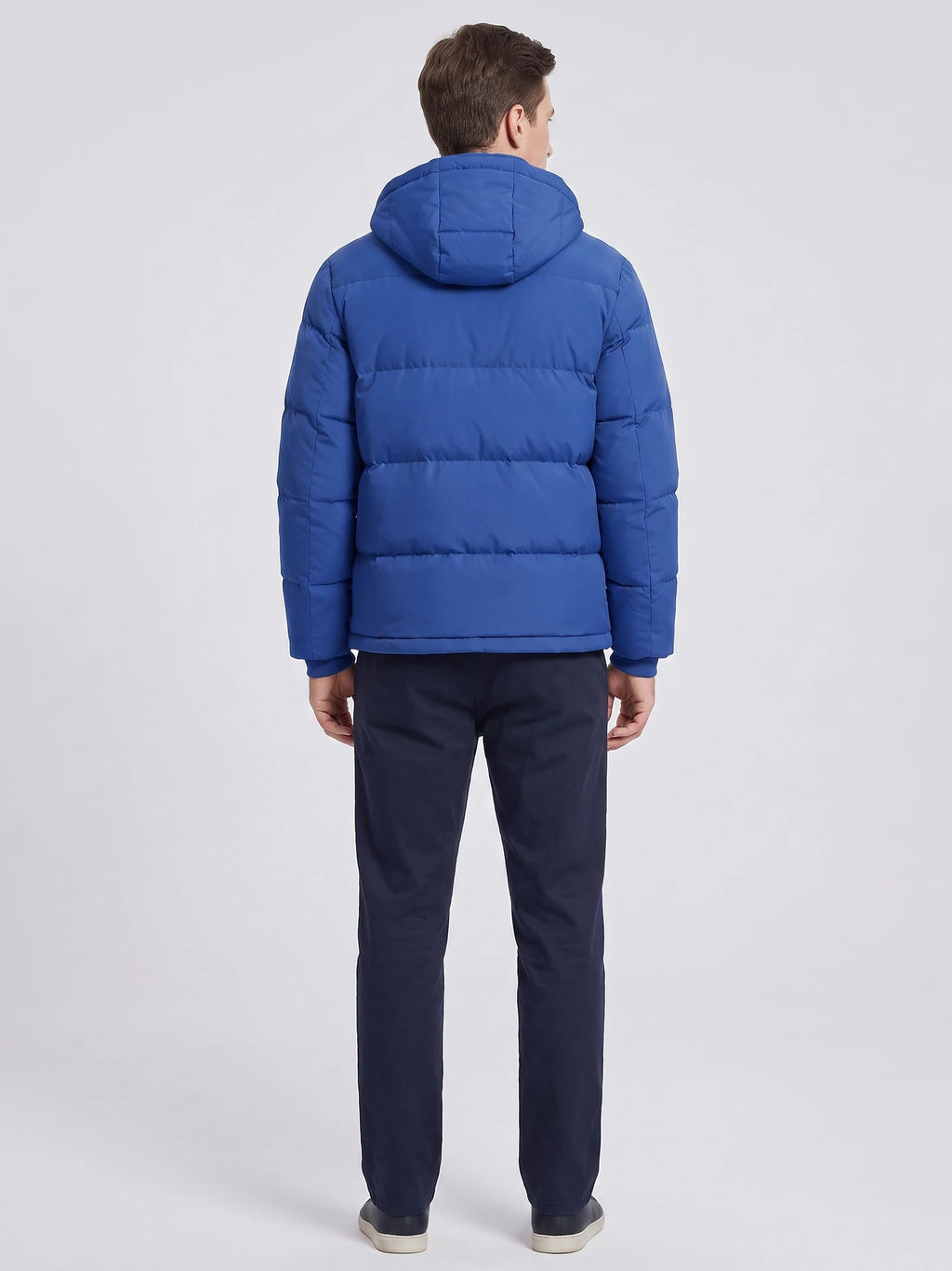 Rear studio view of a model wearing a Blue hooded puffer jacket with horizontal quilted panels.