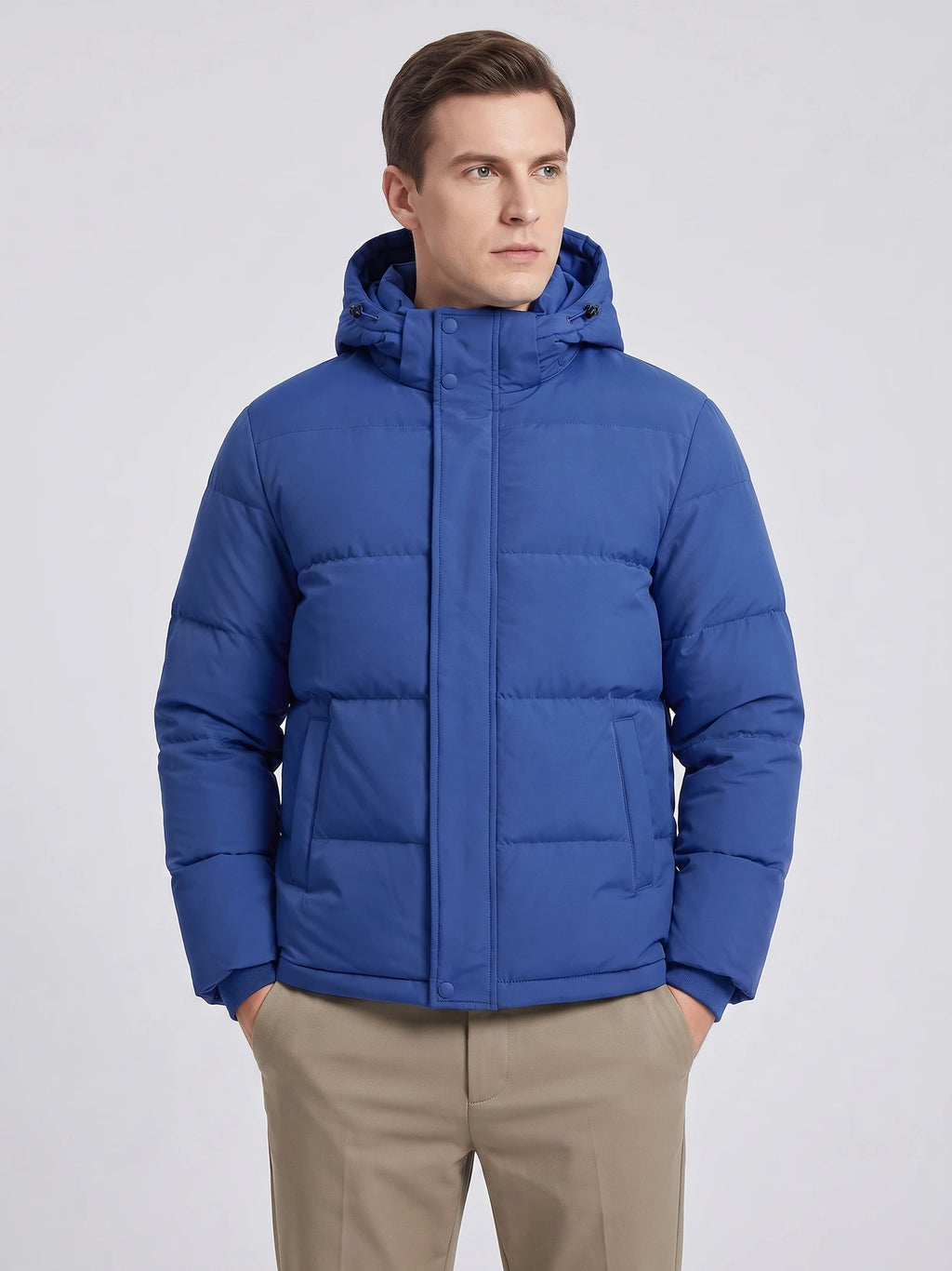 Model wearing a Blue hooded puffer jacket in a front studio view, with quilted panels, snap placket, and angled pockets.