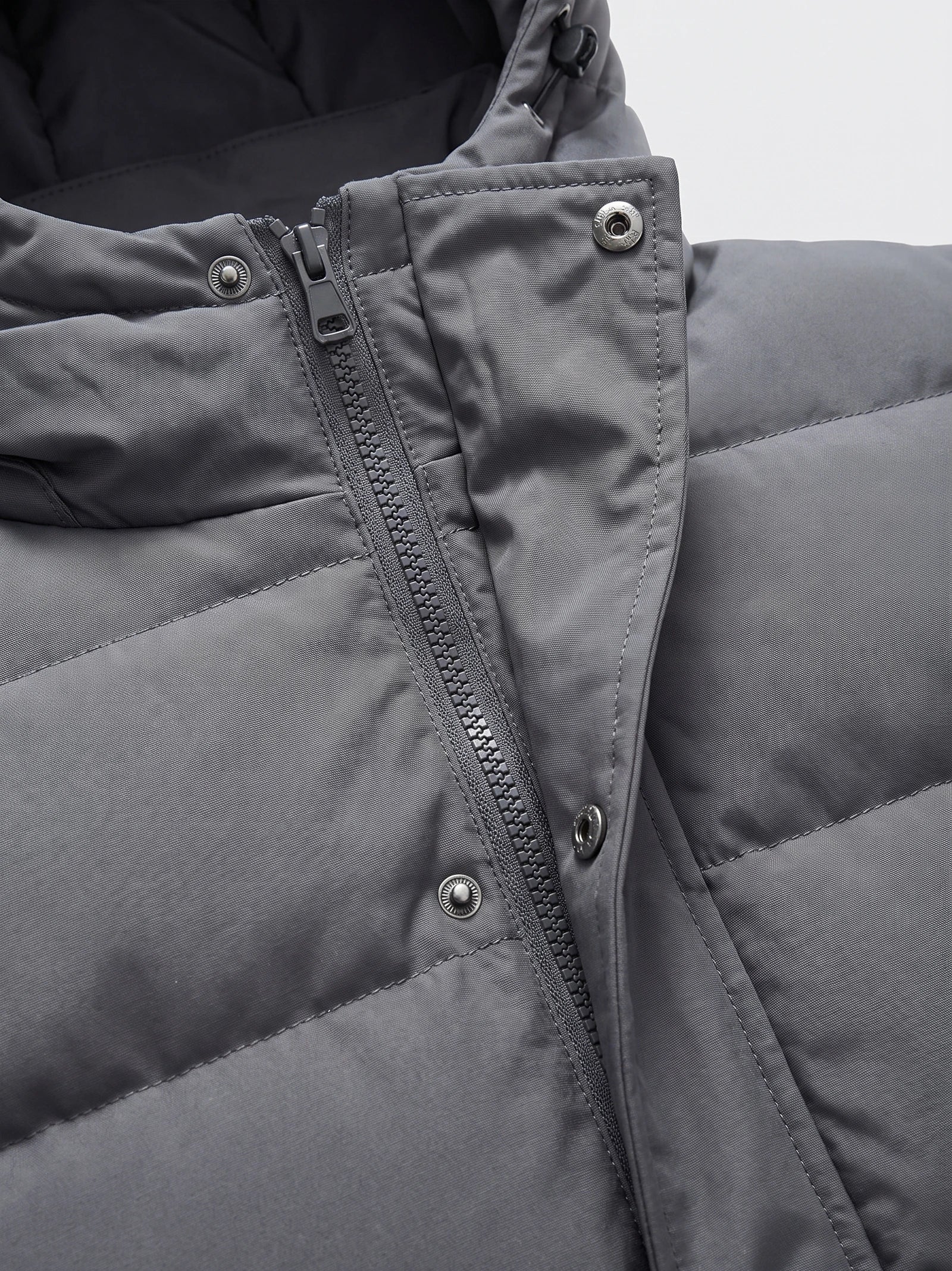 Close-up of the Gray Hooded Puffer Jacket front zipper, snap-button storm flap, and stitched collar.