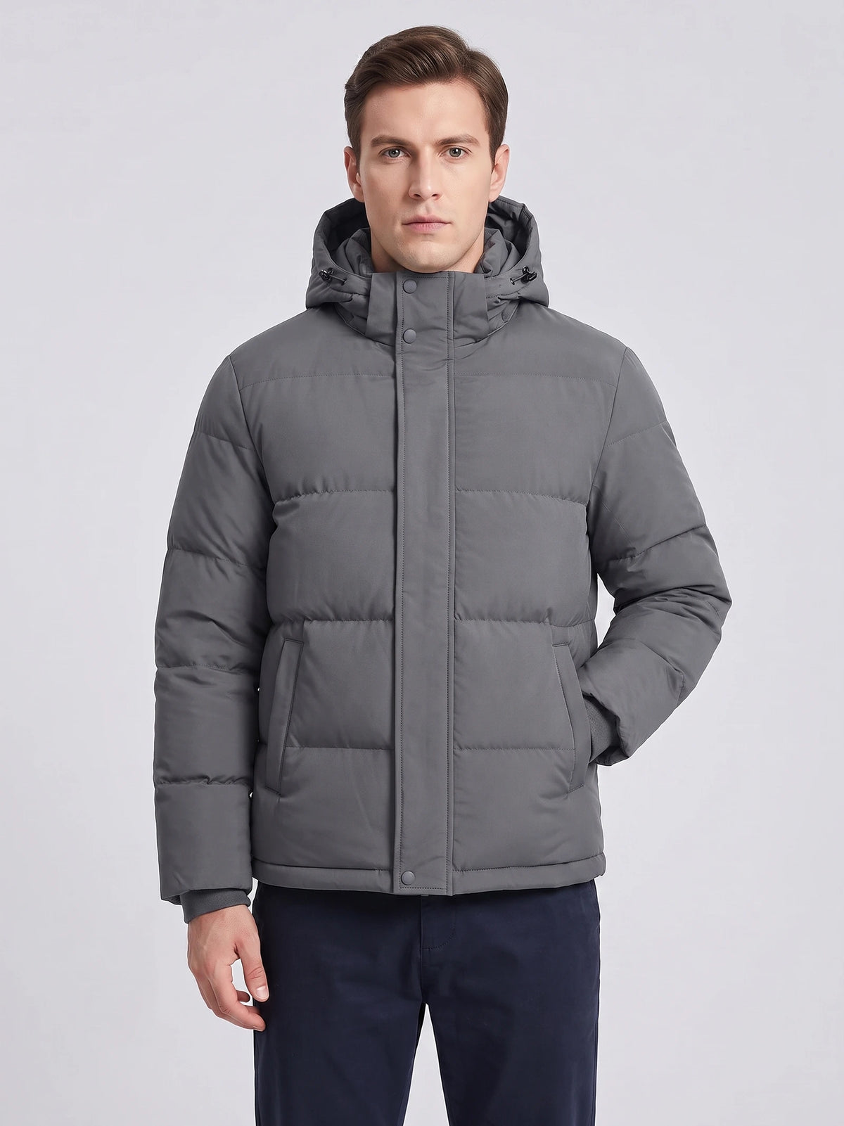 Front studio view of a model wearing a Gray hooded puffer jacket with quilted panels, snap-front closure, and angled pockets.
