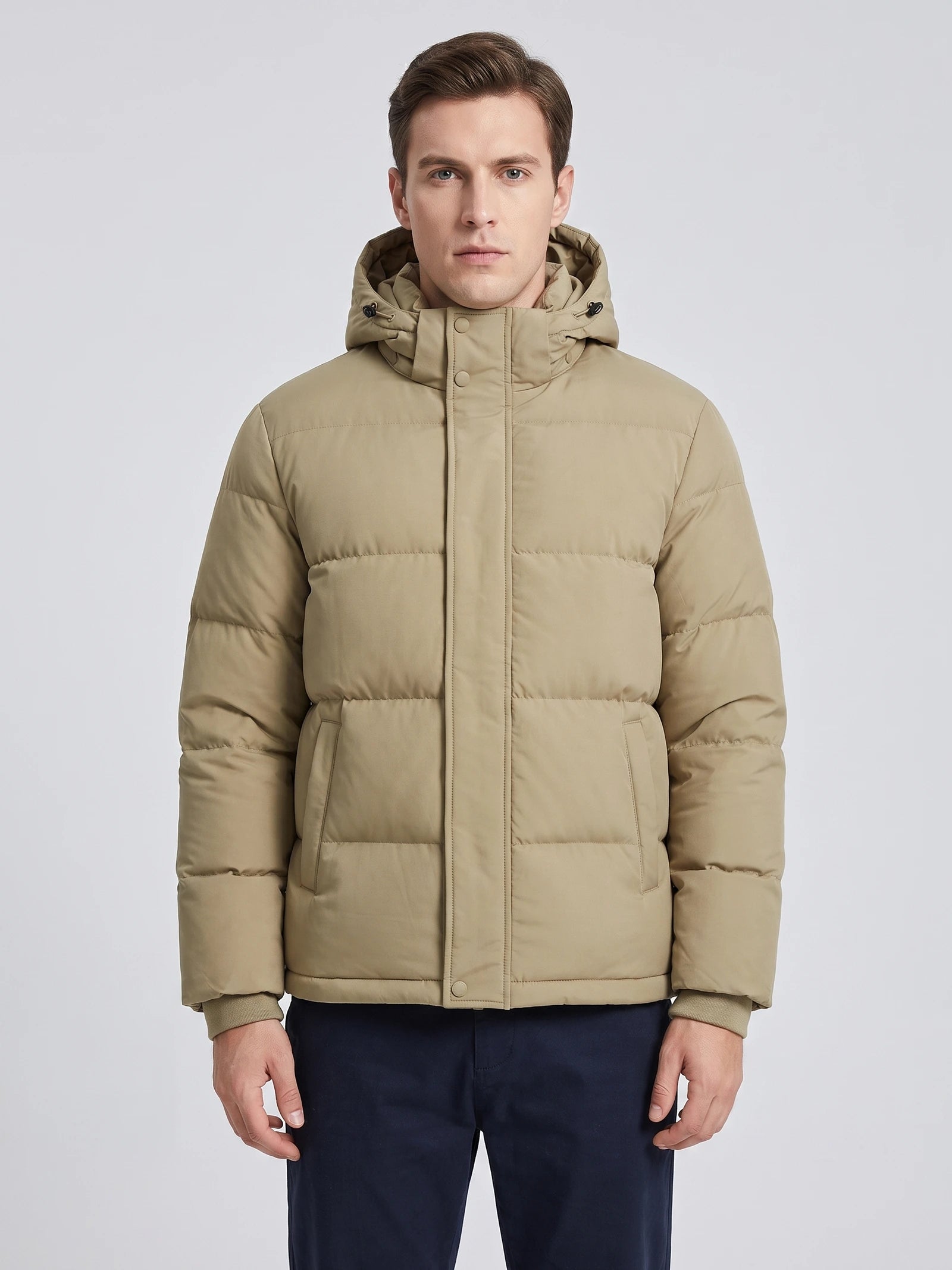 Front studio view of a model wearing a Khaki Hooded Puffer Jacket with quilted panels, snap placket, and front pockets.