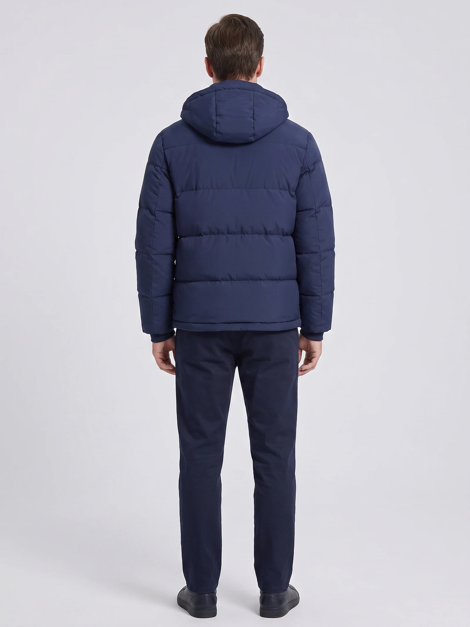 Rear studio view of a model wearing a Navy hooded puffer jacket with horizontal quilted panels.