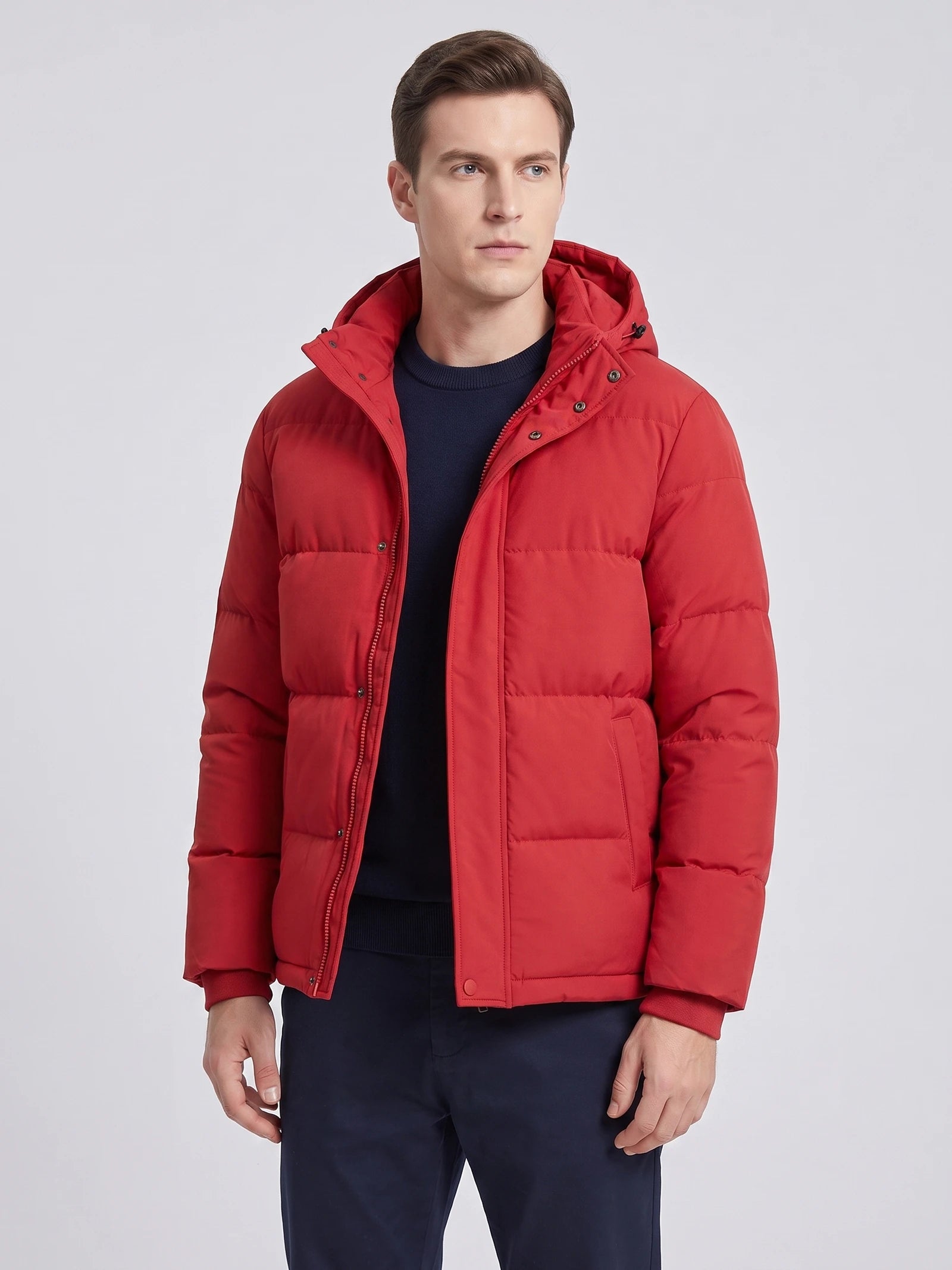 Front studio view of a model wearing a Red hooded puffer jacket with quilted panels, zip-front closure, and flap pockets.