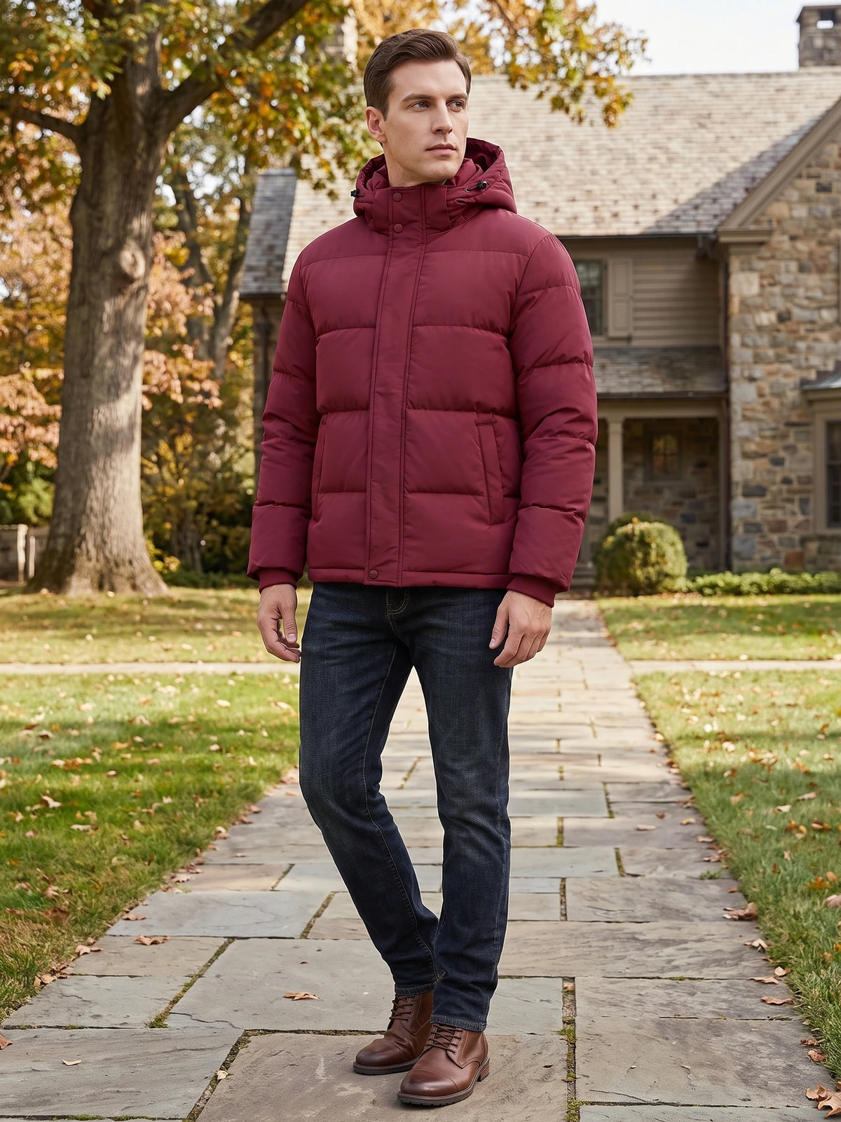 Man wearing a Wine hooded puffer jacket while walking along a stone path outside a home.