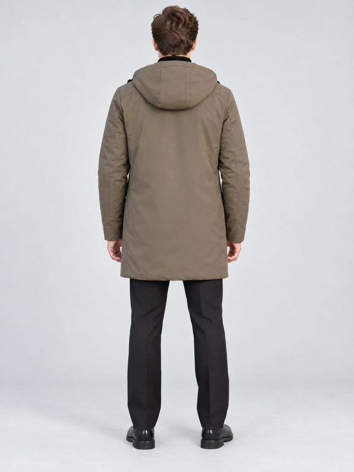 Rear studio view of a model wearing a Brown men’s hooded trench coat with a long, streamlined back.