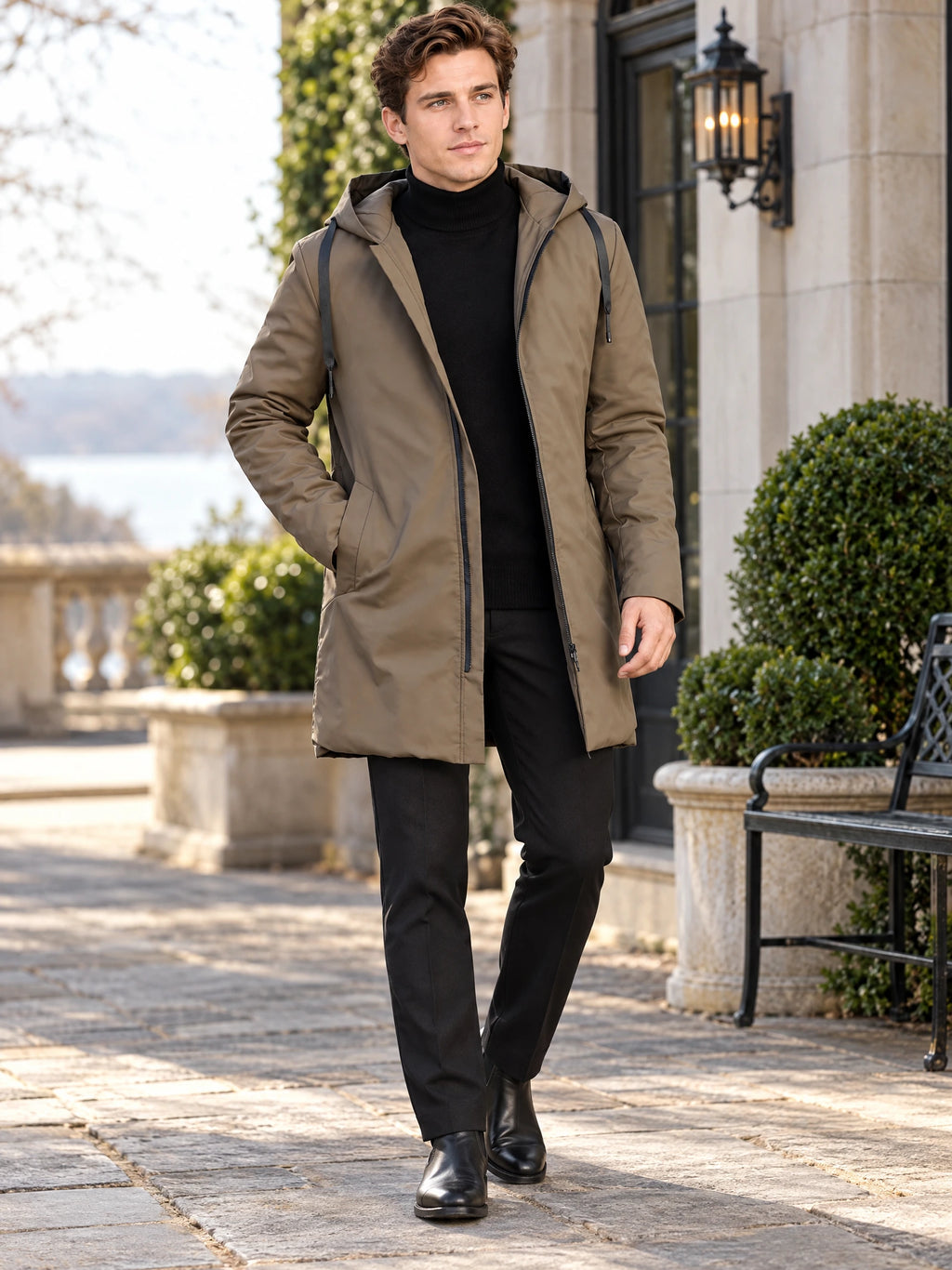 Model walking outdoors in a Brown men’s hooded trench coat with a zip front and drawstring hood.