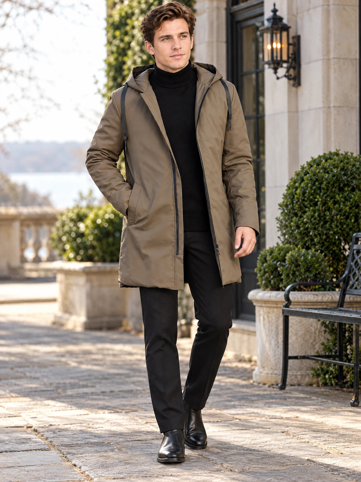 Model walking outdoors in a Brown men’s hooded trench coat with a zip front and drawstring hood.