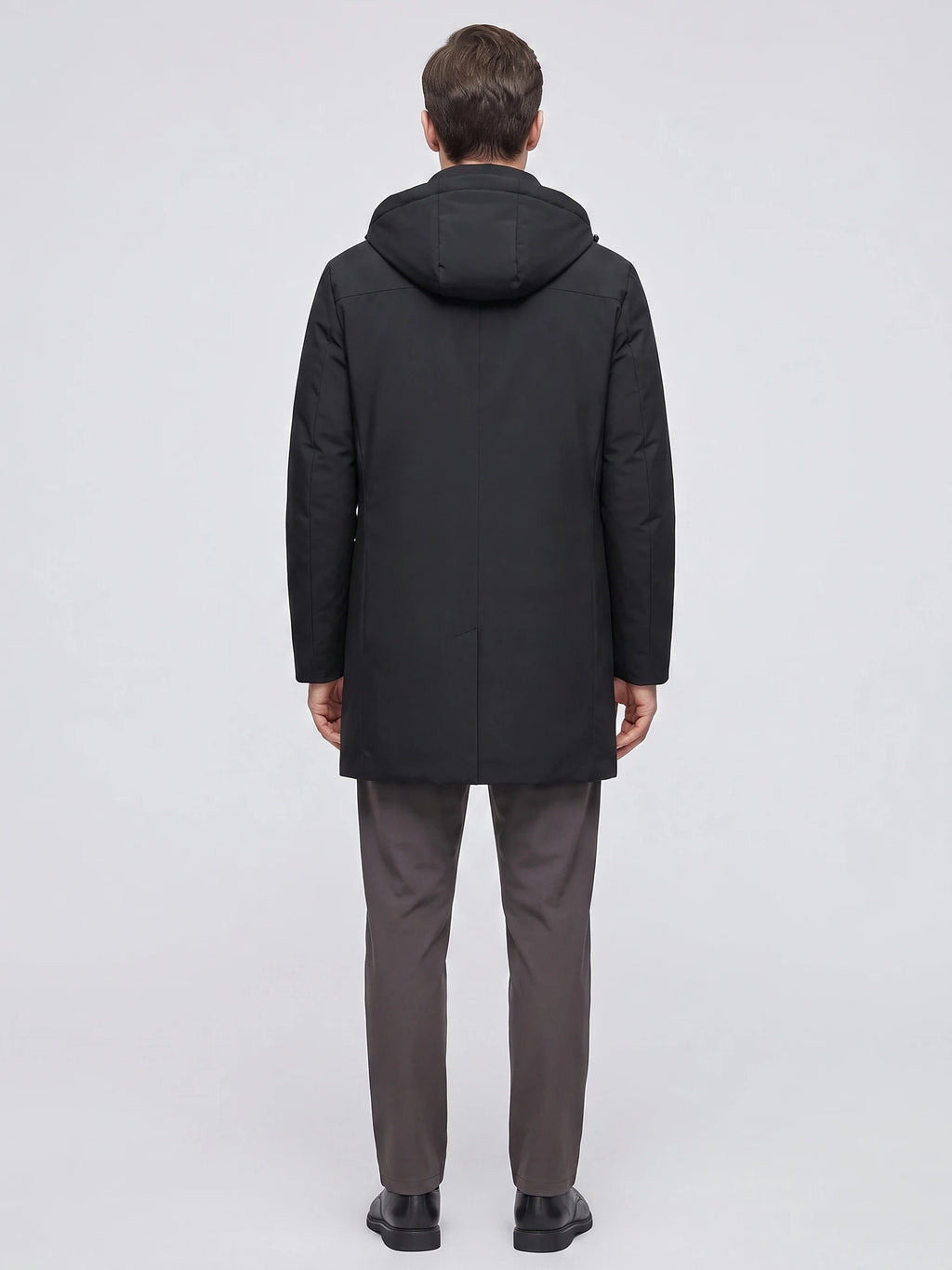 Rear studio view of a model wearing a Black Hooded Trench Coat with a smooth longline back and padded hood.