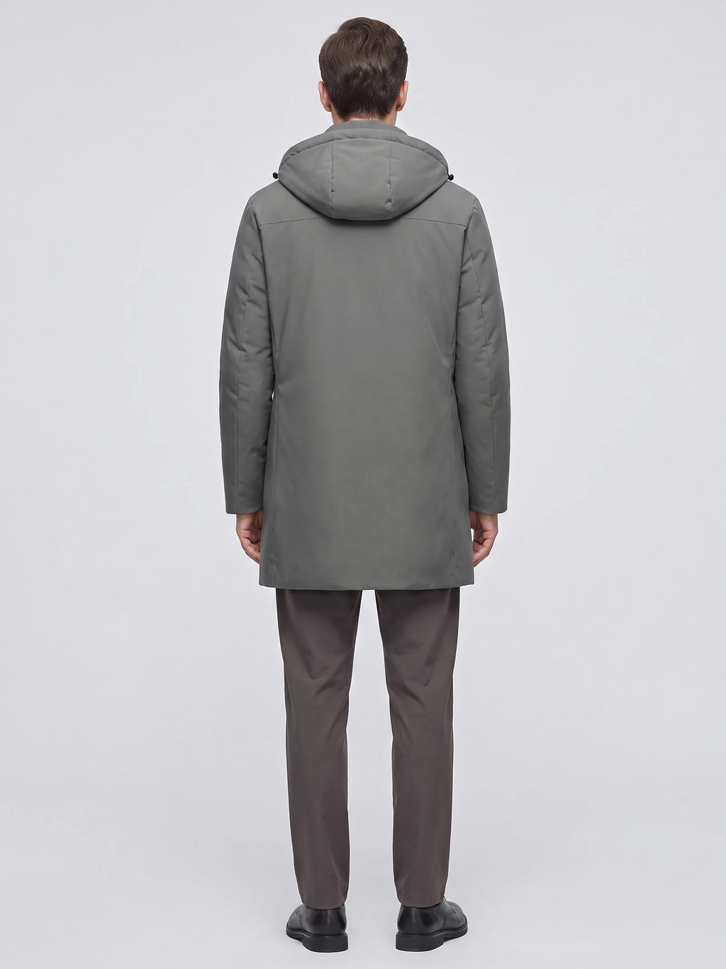 Rear studio view of a model wearing a Gray men's Hooded Trench Coat with a padded hood and straight mid-length silhouette.