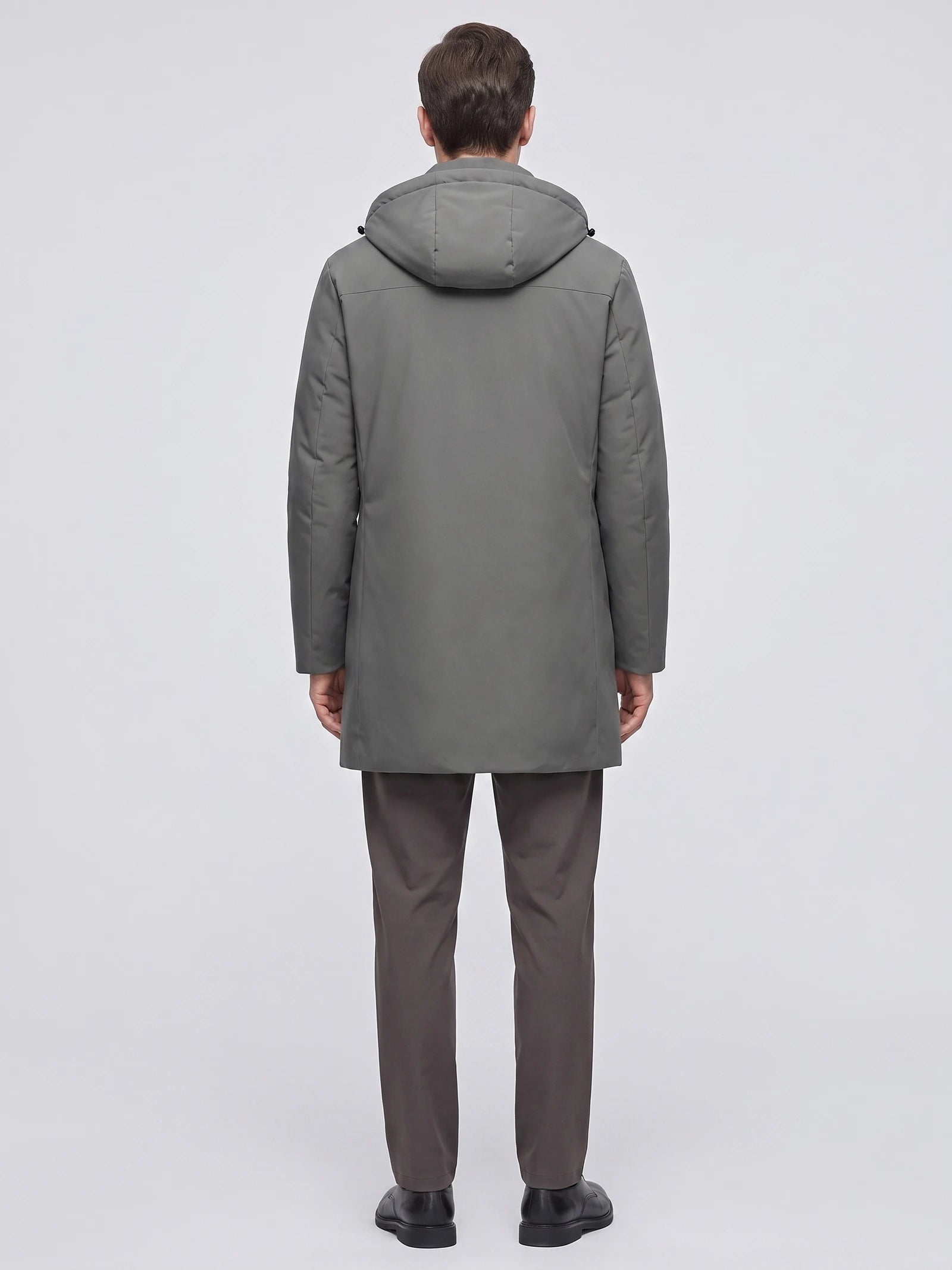 Rear studio view of a model wearing a Gray men's Hooded Trench Coat with a padded hood and straight mid-length silhouette.