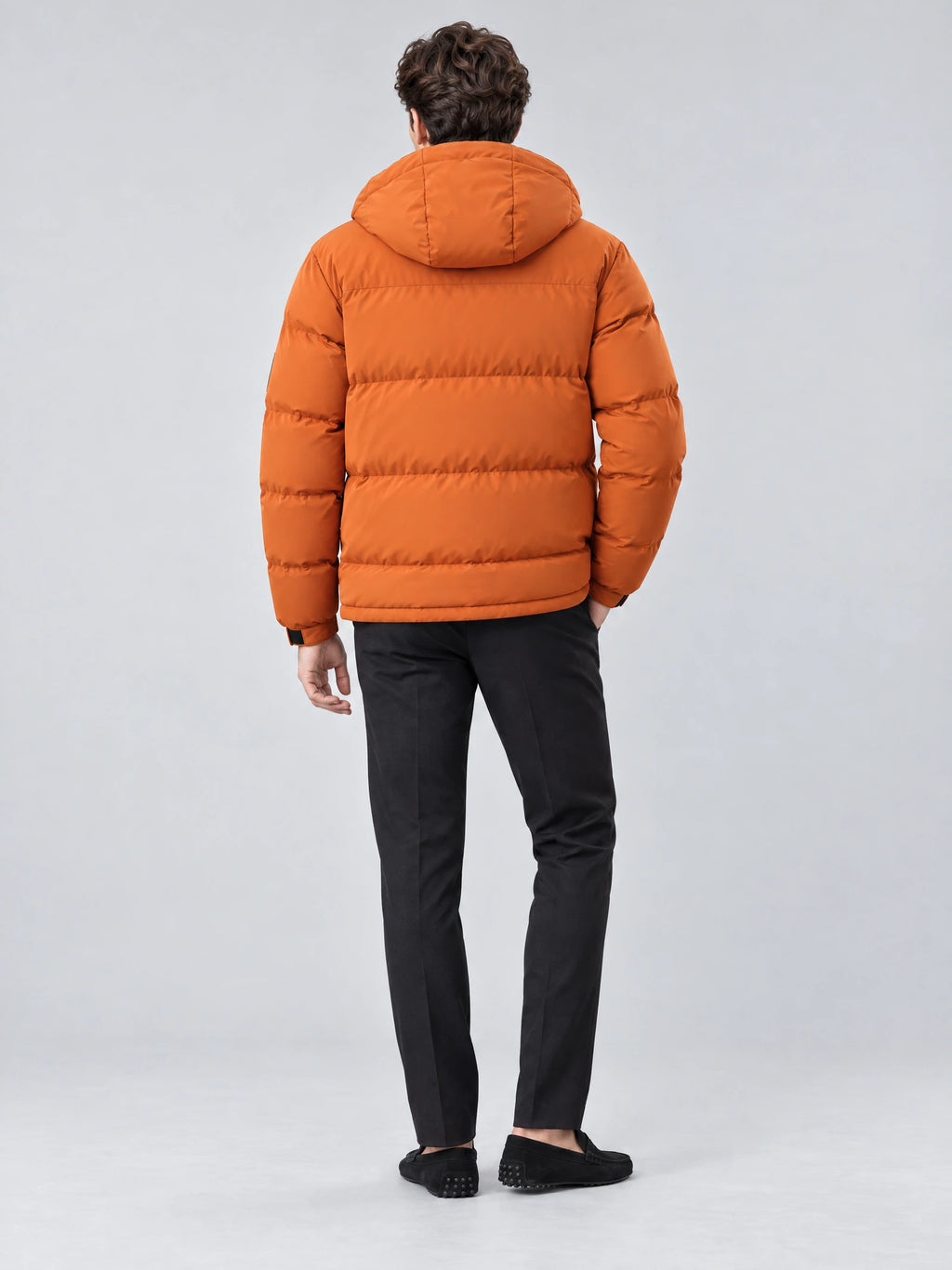 Rear studio view of a model wearing an Orange hooded winter jacket with quilted padding.