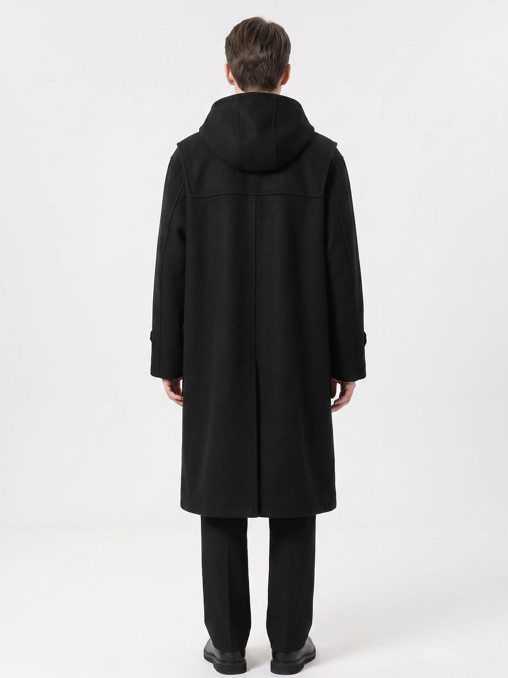 Rear studio view of a model wearing a Black wool trench coat with a hood, back yoke, and center back seam.