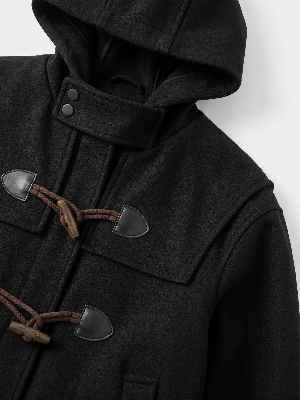 Close-up of the Black wool men’s trench coat hood, snap-tab collar, and toggle fastenings.