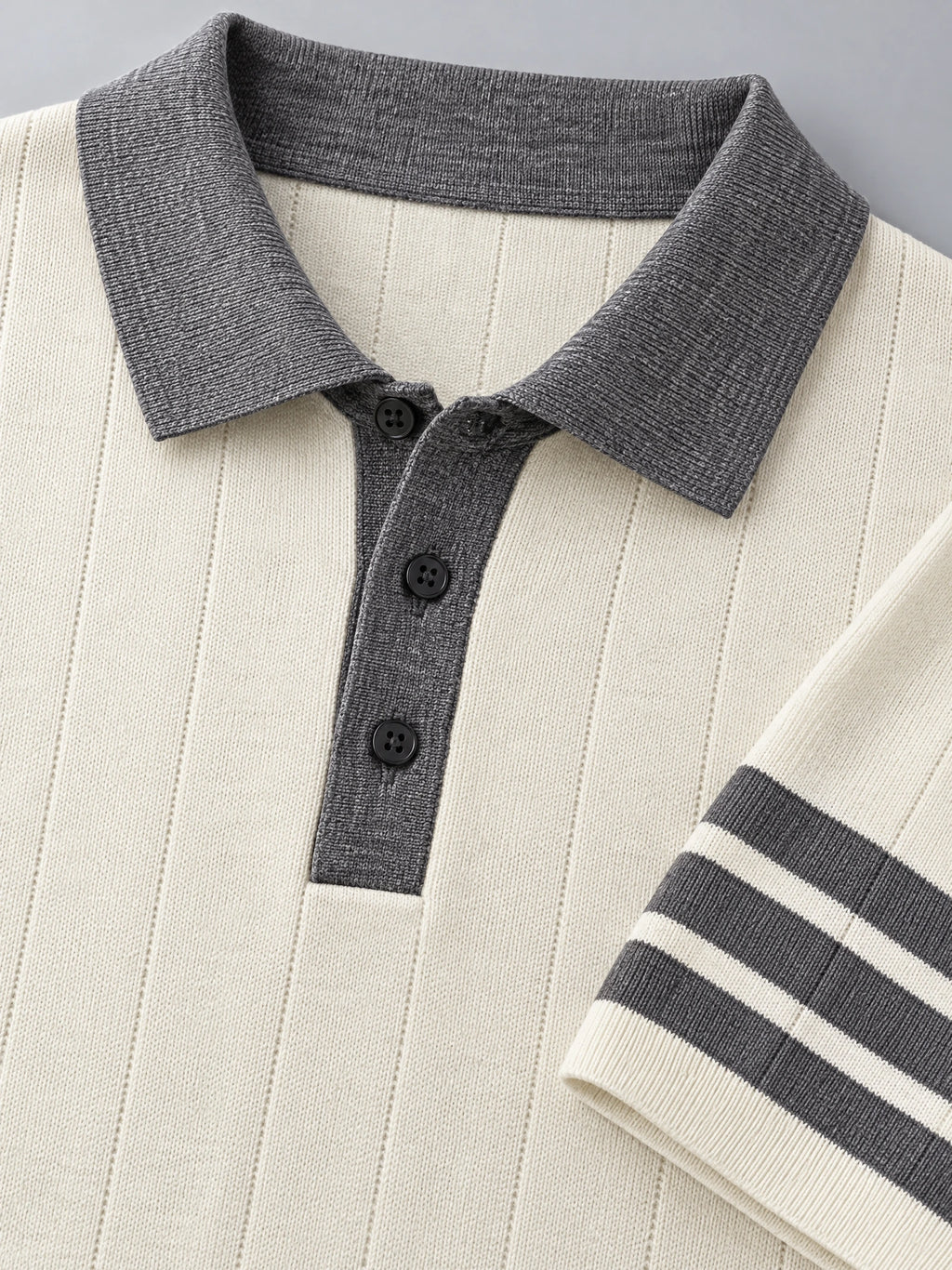 Beige knit polo detail showing a ribbed collar, three-button placket, textured knit, and striped sleeve cuff.