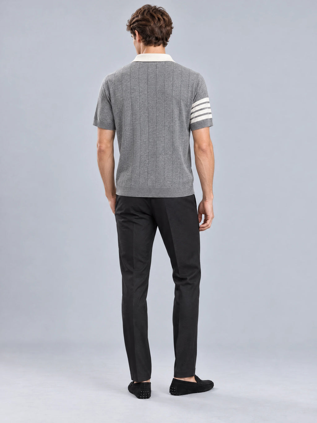 Rear view of a model wearing a Gray Knit Polo with vertical knit texture and striped short sleeves.