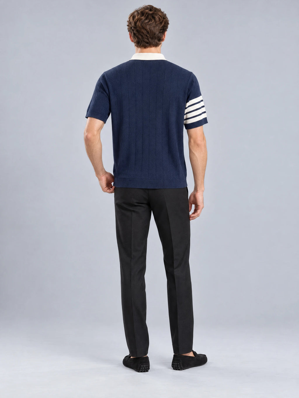 Rear studio view of a model wearing a Navy Knit Polo with a ribbed hem and striped short-sleeve cuff.