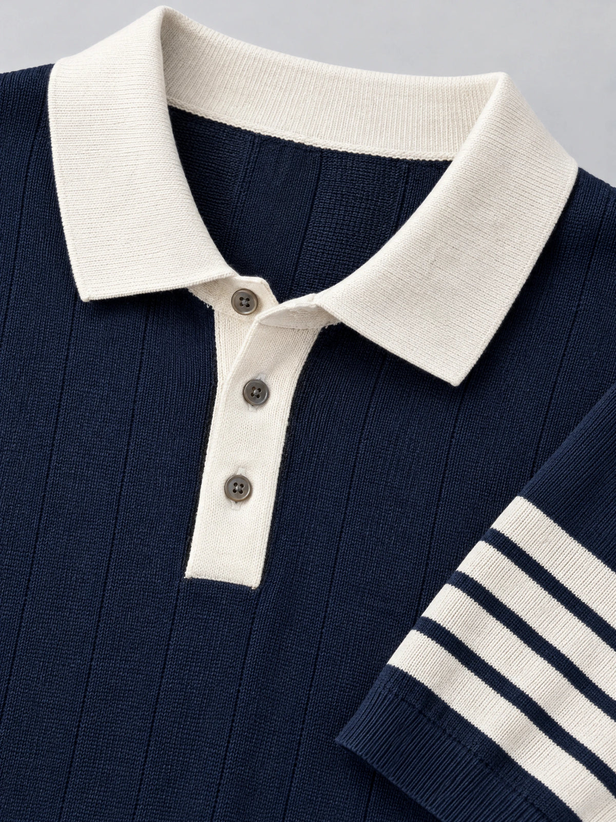 Navy Knit Polo close-up showing the ribbed collar, three-button placket, and striped sleeve cuff.