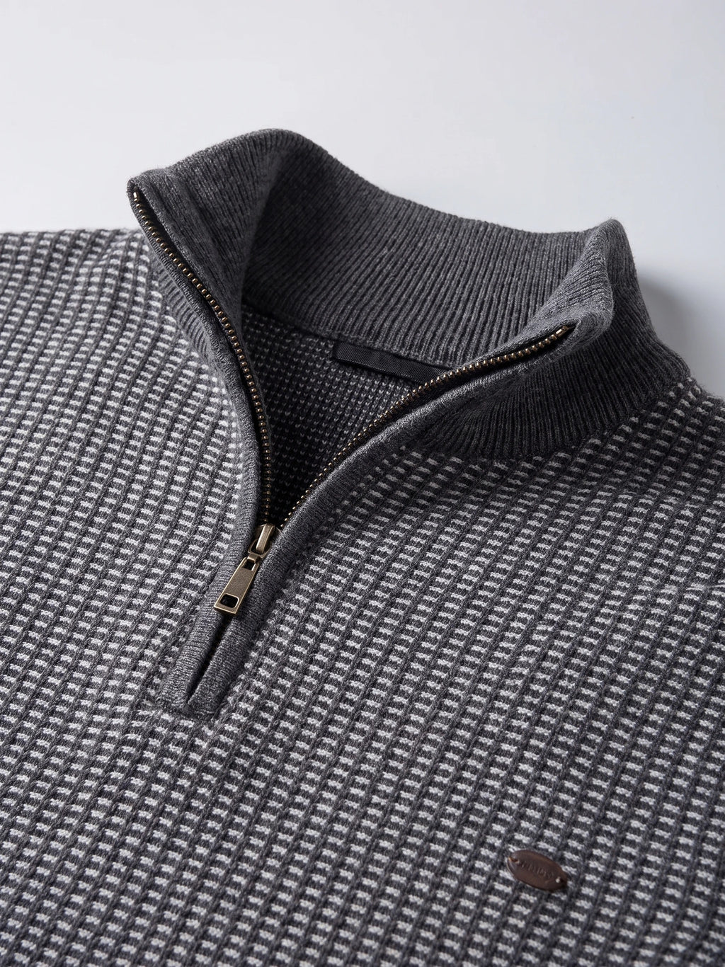Close-up of the Gray knit quarter-zip sweater showing its ribbed mock neck, metal zipper, and textured striped knit.