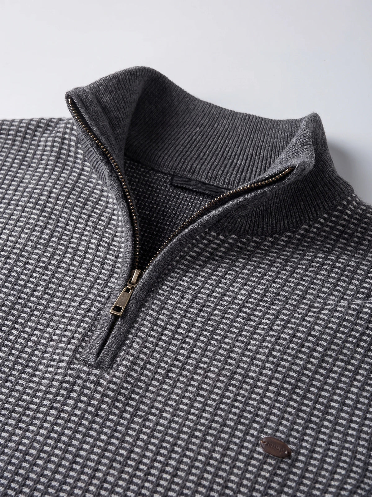 Close-up of the Gray knit quarter-zip sweater showing its ribbed mock neck, metal zipper, and textured striped knit.