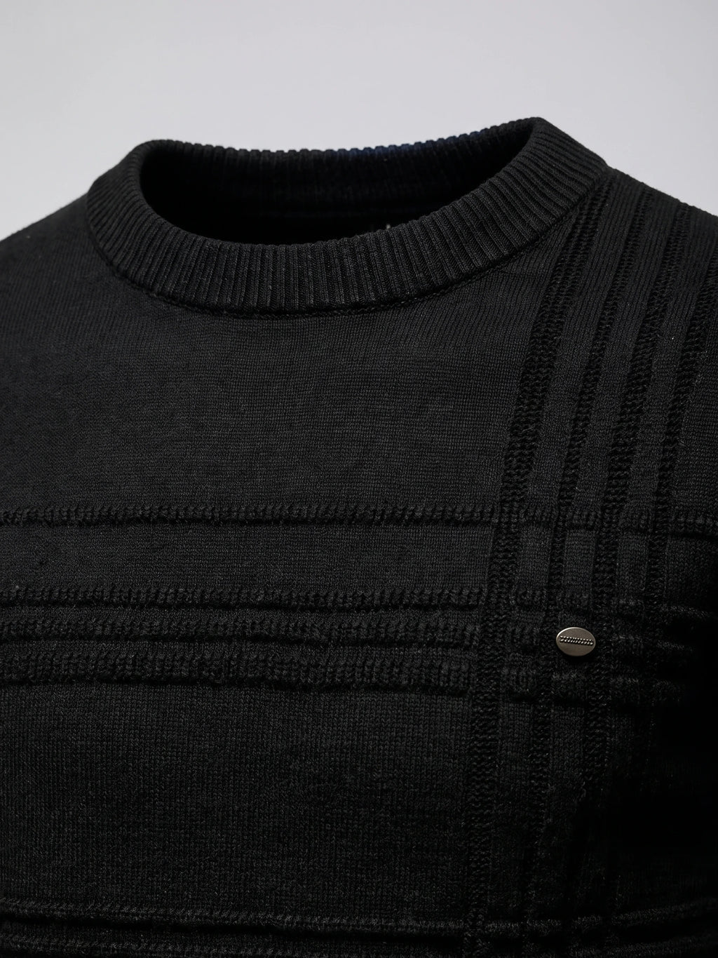Close-up of the Black knitted cotton sweater’s ribbed crewneck, textured knit panels, and chest button detail.