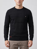 Front studio view of a model wearing a Black knitted cotton crewneck sweater with textured panel stitching and ribbed trim.