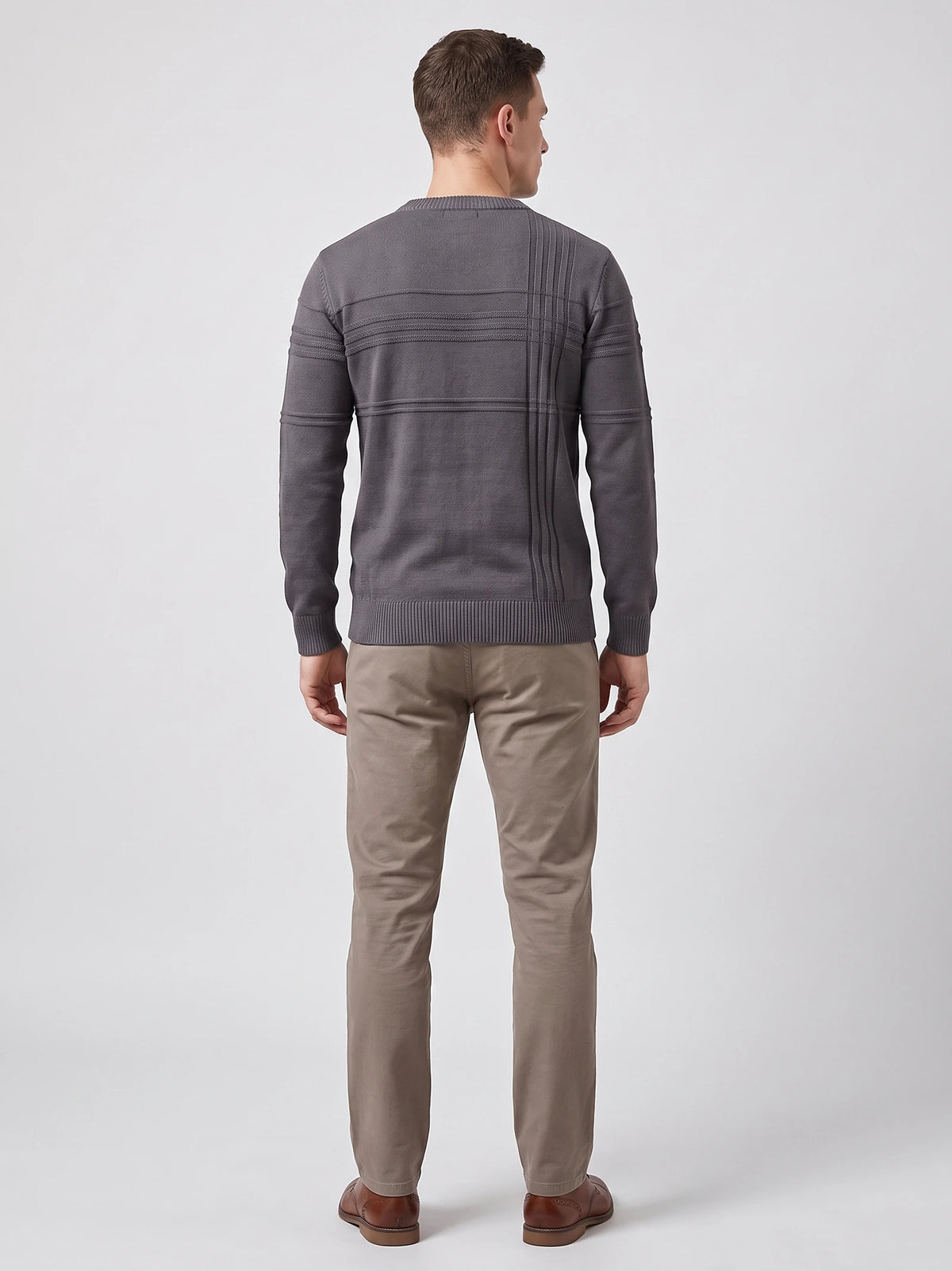 Rear studio view of a model wearing a Charcoal knitted cotton crewneck sweater with ribbed trim and vertical textured back detailing.