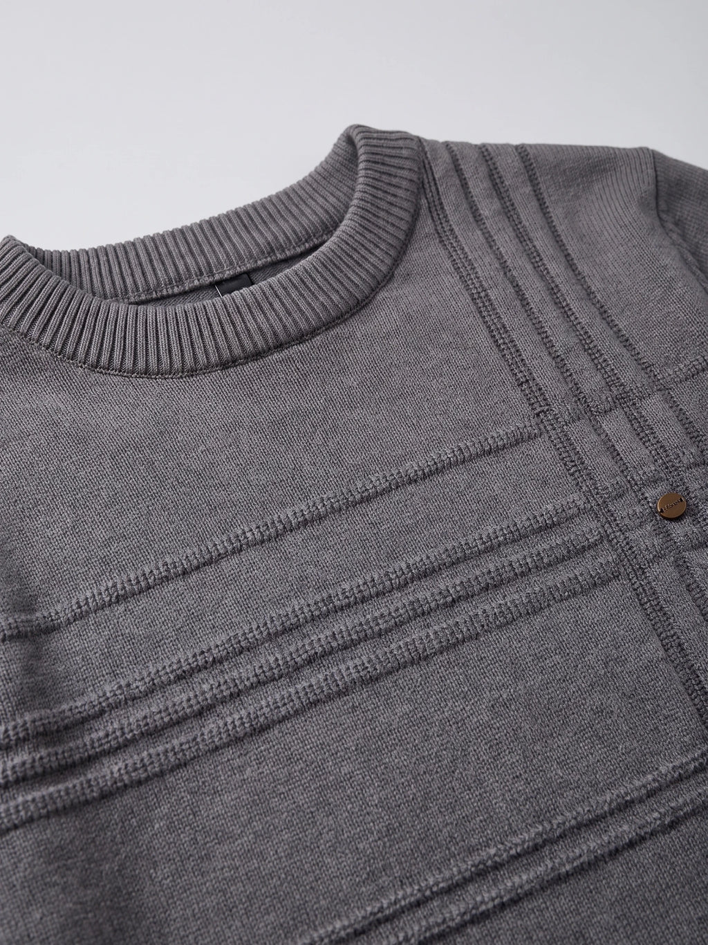 Close-up of the Charcoal knitted cotton sweater’s ribbed crewneck and textured geometric knit pattern.
