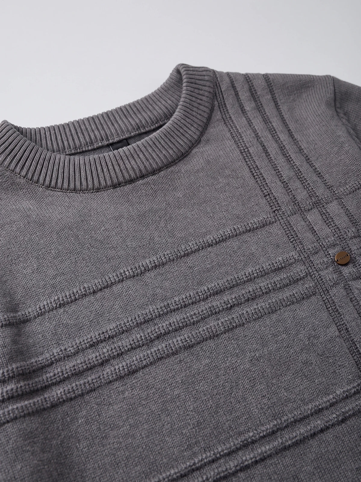 Close-up of the Charcoal knitted cotton sweater’s ribbed crewneck and textured geometric knit pattern.