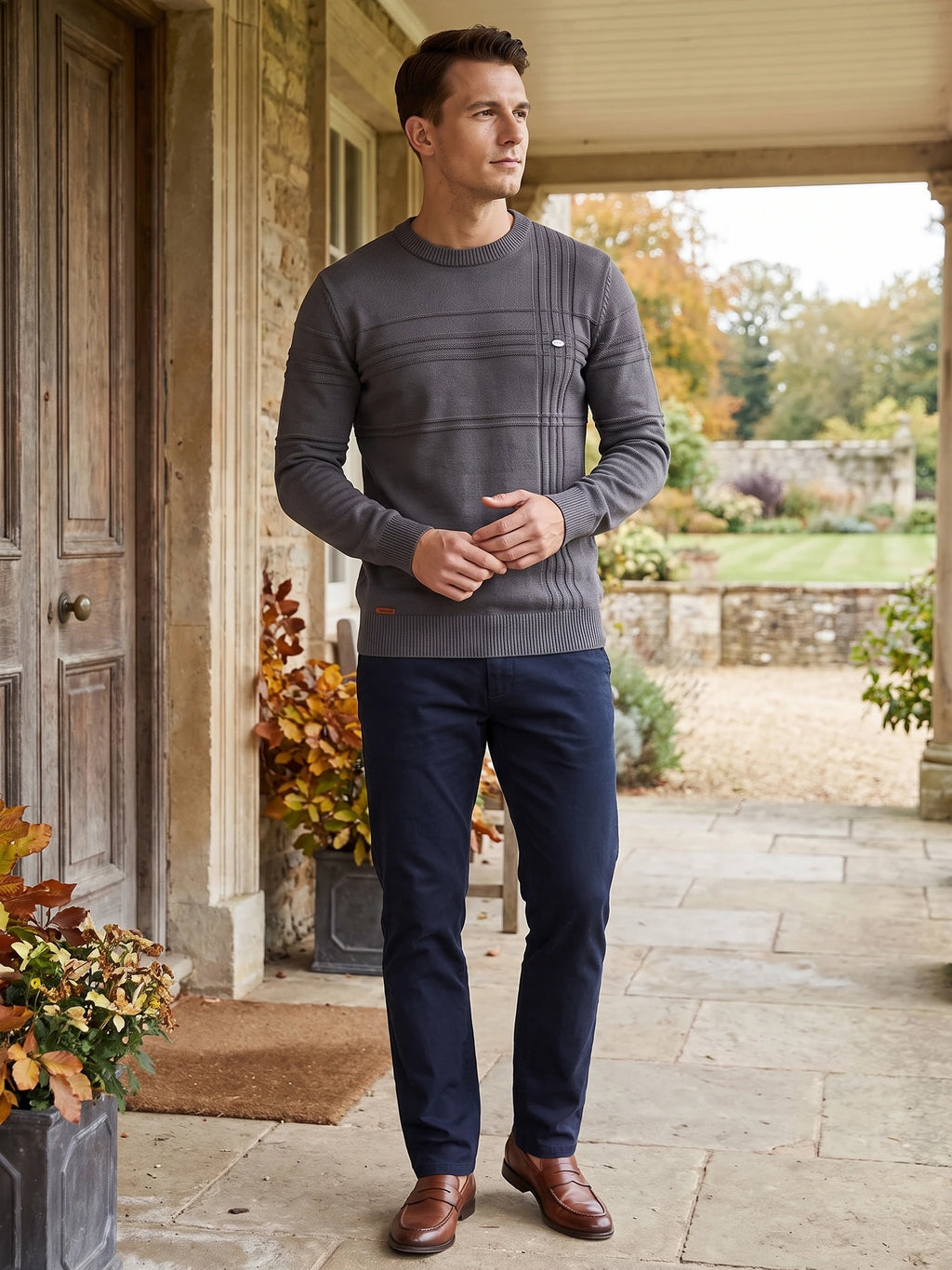 Man wearing a Charcoal knitted cotton crewneck sweater with textured stitched panels on a covered porch.