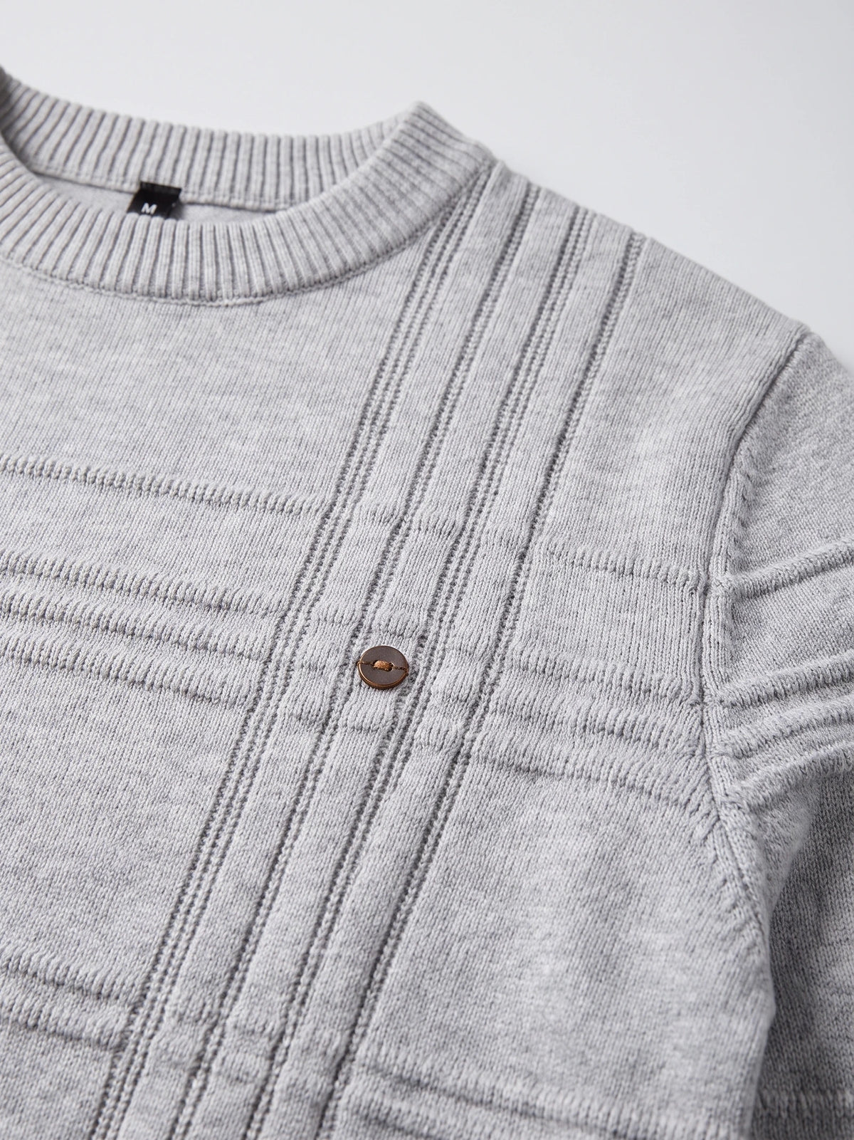Close-up of the Gray knitted cotton sweater showing its ribbed crewneck, textured vertical knit pattern, shoulder seam, and button detail.