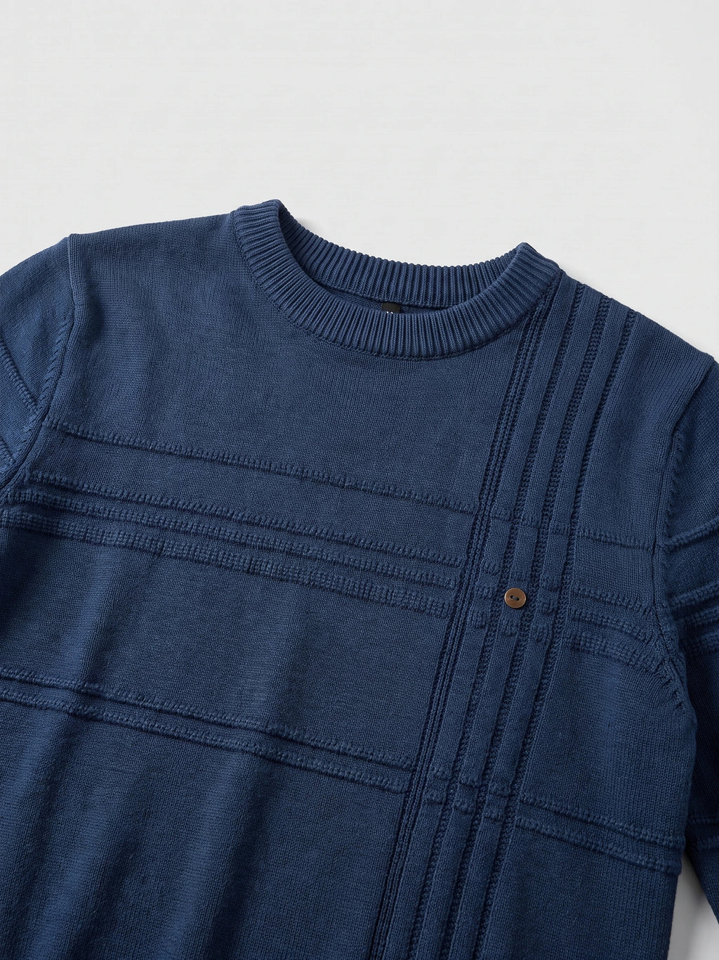Close-up of a Navy knitted cotton sweater with a ribbed crewneck, textured knit panels, and a decorative buttoned vertical placket.