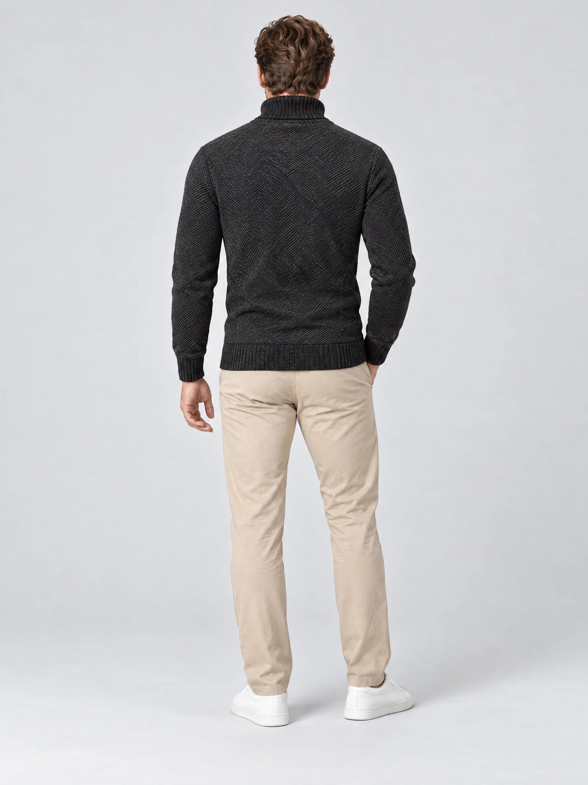 Rear studio view of a model wearing a Black knitted turtleneck sweater with ribbed cuffs and hem.