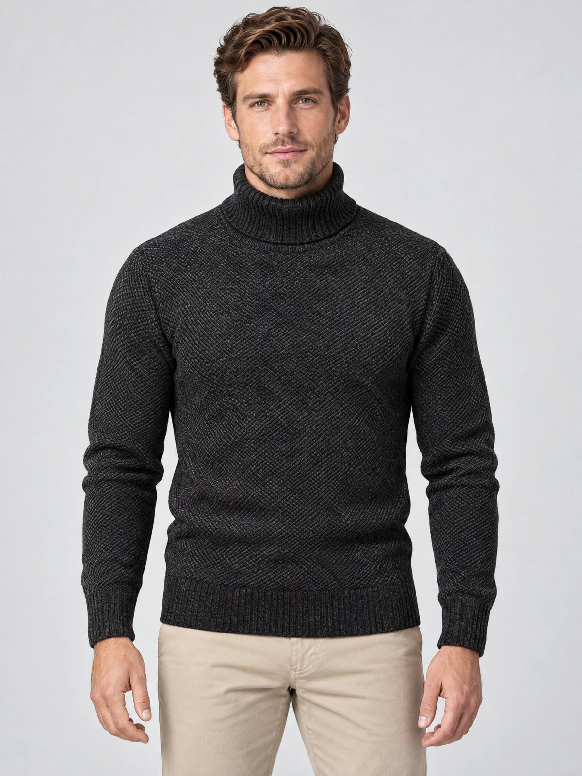 Front studio view of a model wearing a Black knitted turtleneck sweater with textured diagonal knit and ribbed trim.