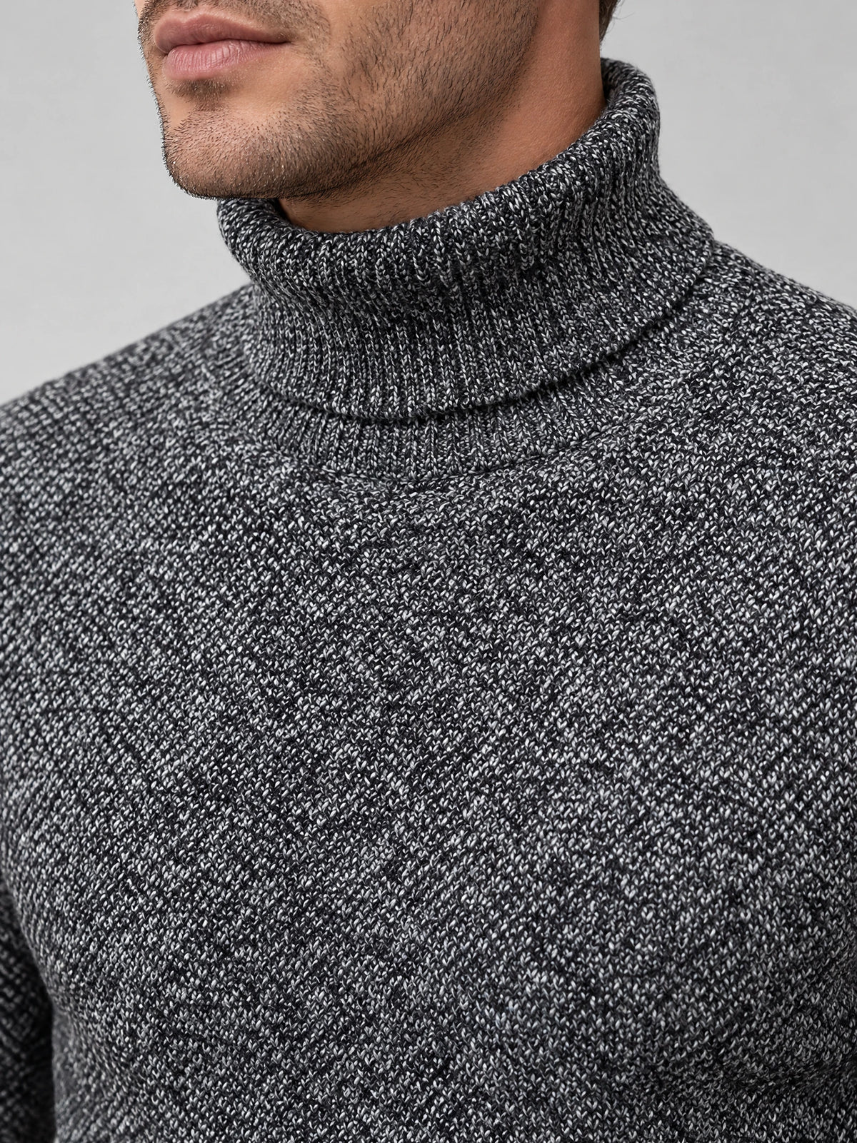 Close-up of a Gray knitted turtleneck sweater showing its textured wool knit and folded ribbed collar.