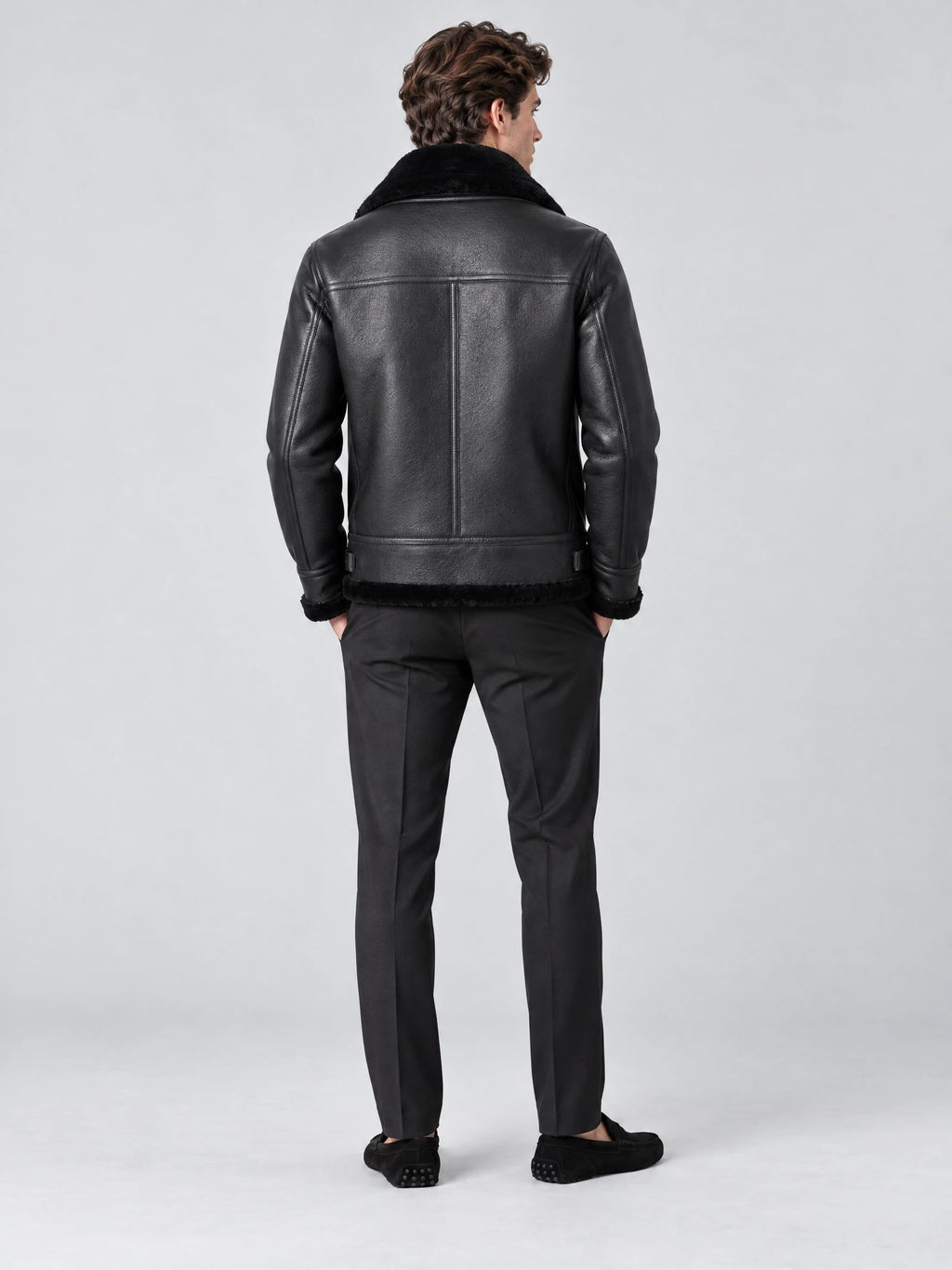 Rear studio view of a model wearing a Black Leather Aviator Jacket with a shearling-style collar, stitched back panel, and trimmed hem.