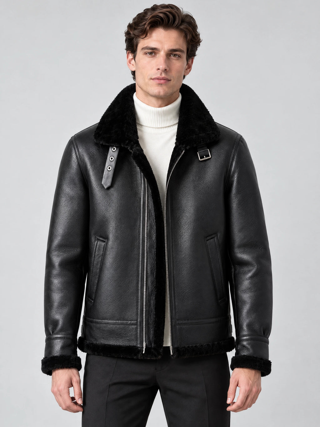 Front studio view of a model wearing a Black Leather Aviator Jacket with a plush collar, zip front, buckle tabs, and angled pockets.